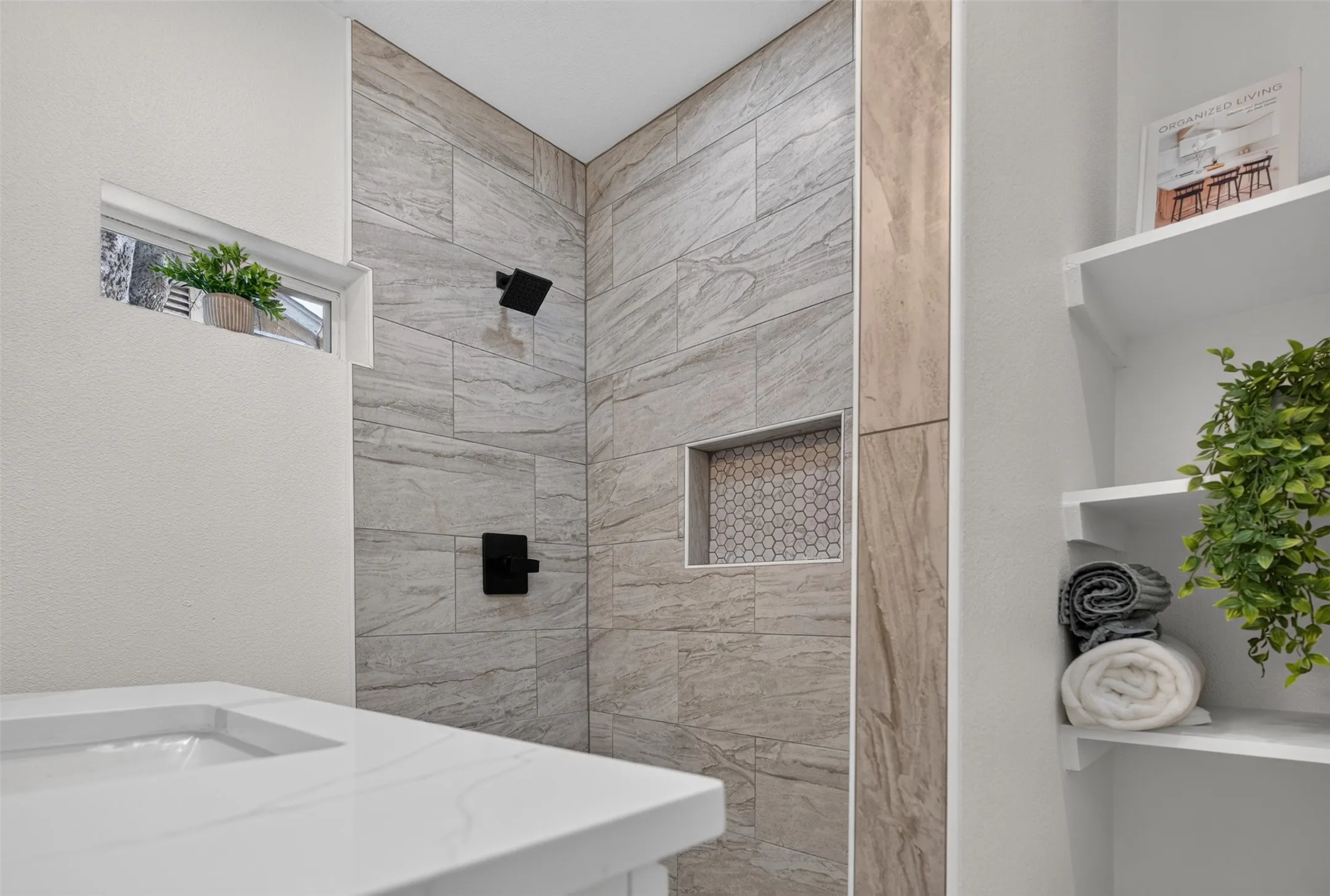 Spa-inspired bathroom featuring a walk-in shower with large-format wood-finish tile surround, dual black matte showerheads, and a recessed niche
