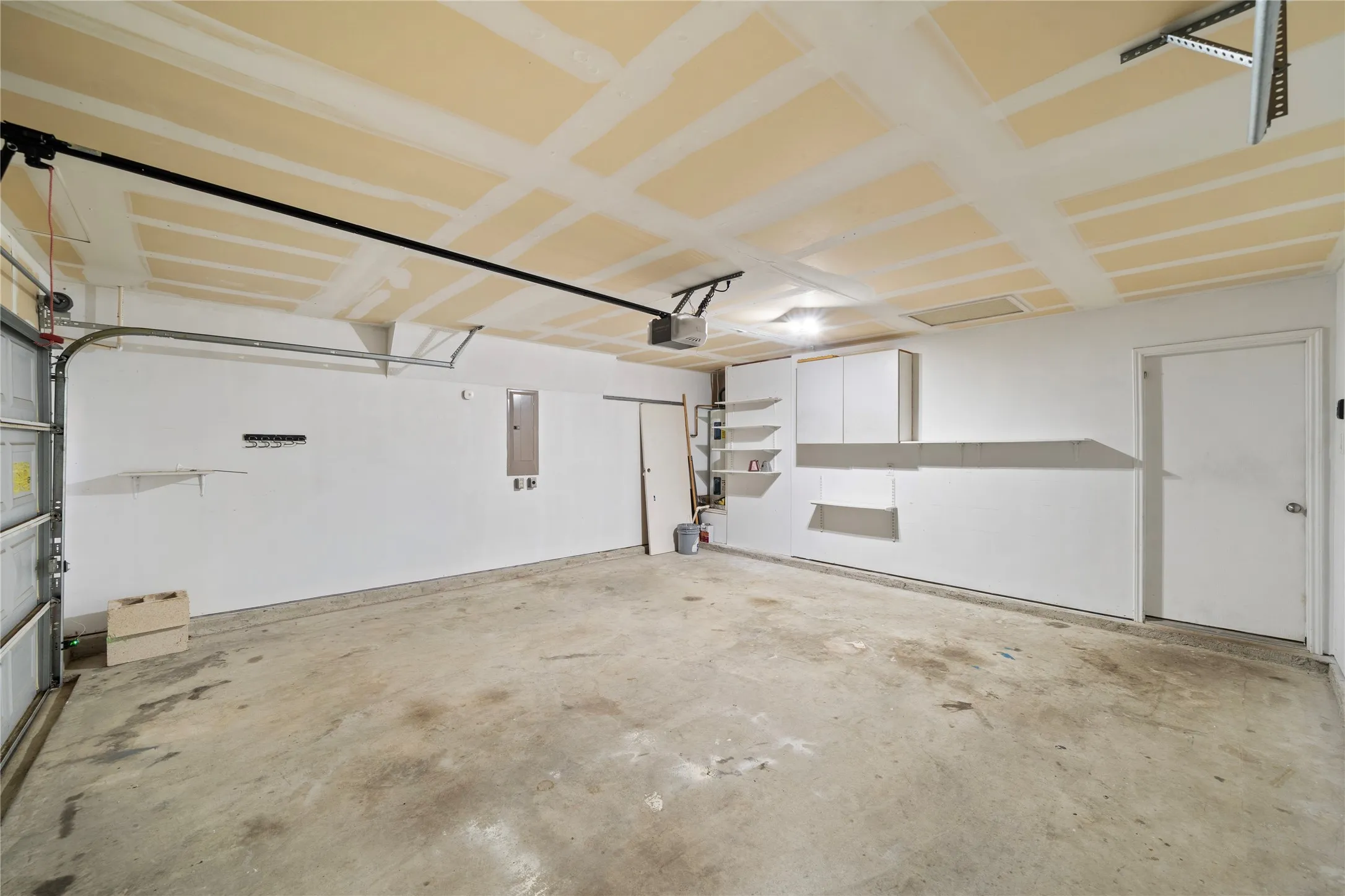 Garage with concrete flooring, overhead lighting, and built-in white cabinetry