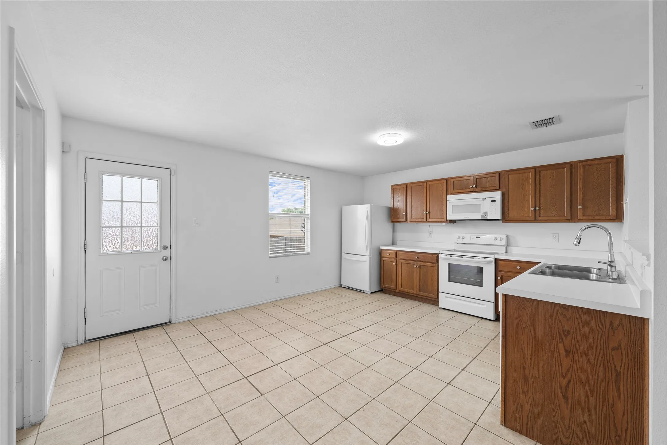 Kitchen featuring wood-finish cabinetry, white countertops, tile flooring, and white appliances
