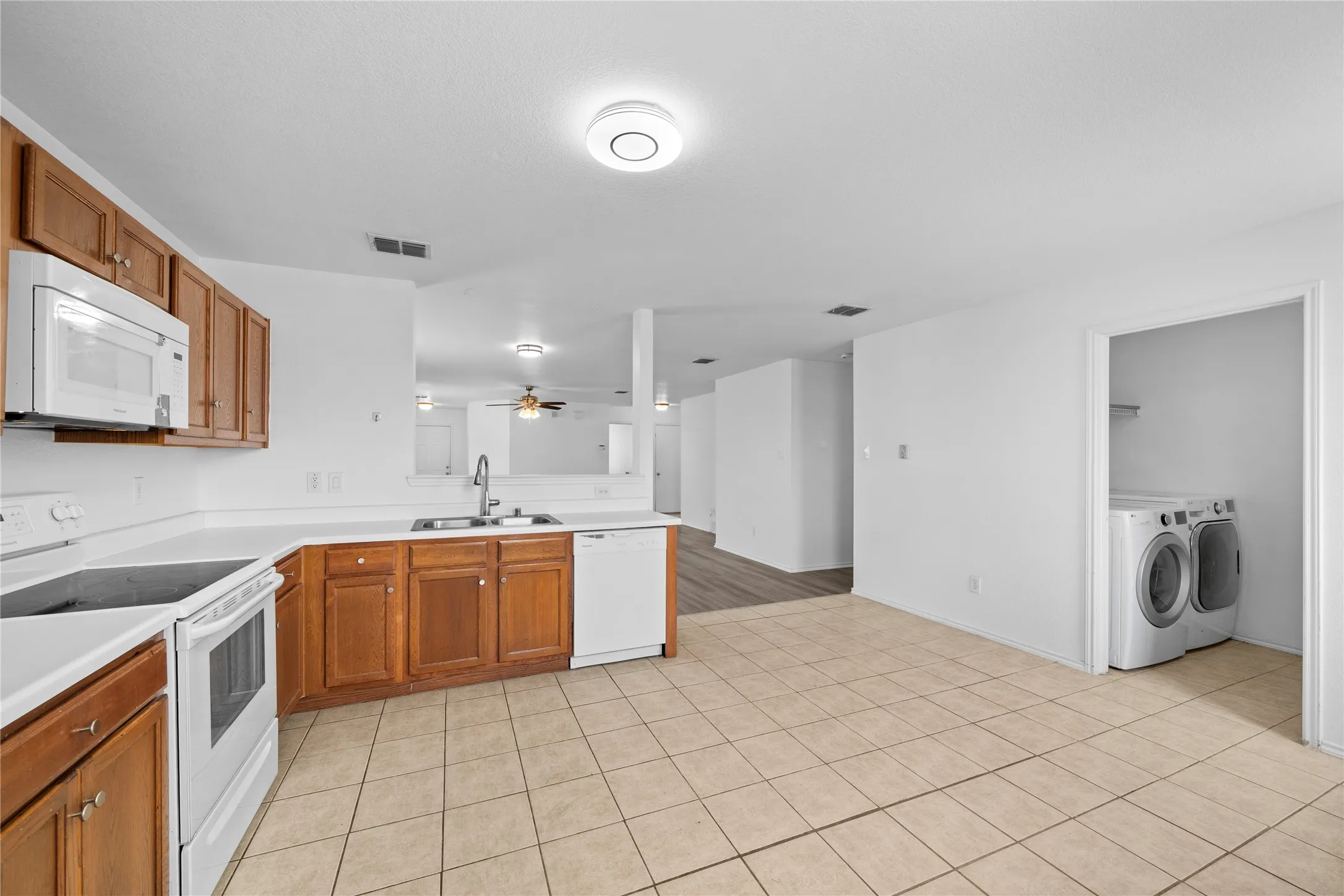 Kitchen featuring wood cabinetry, white countertops, built-in microwave, and tile flooring