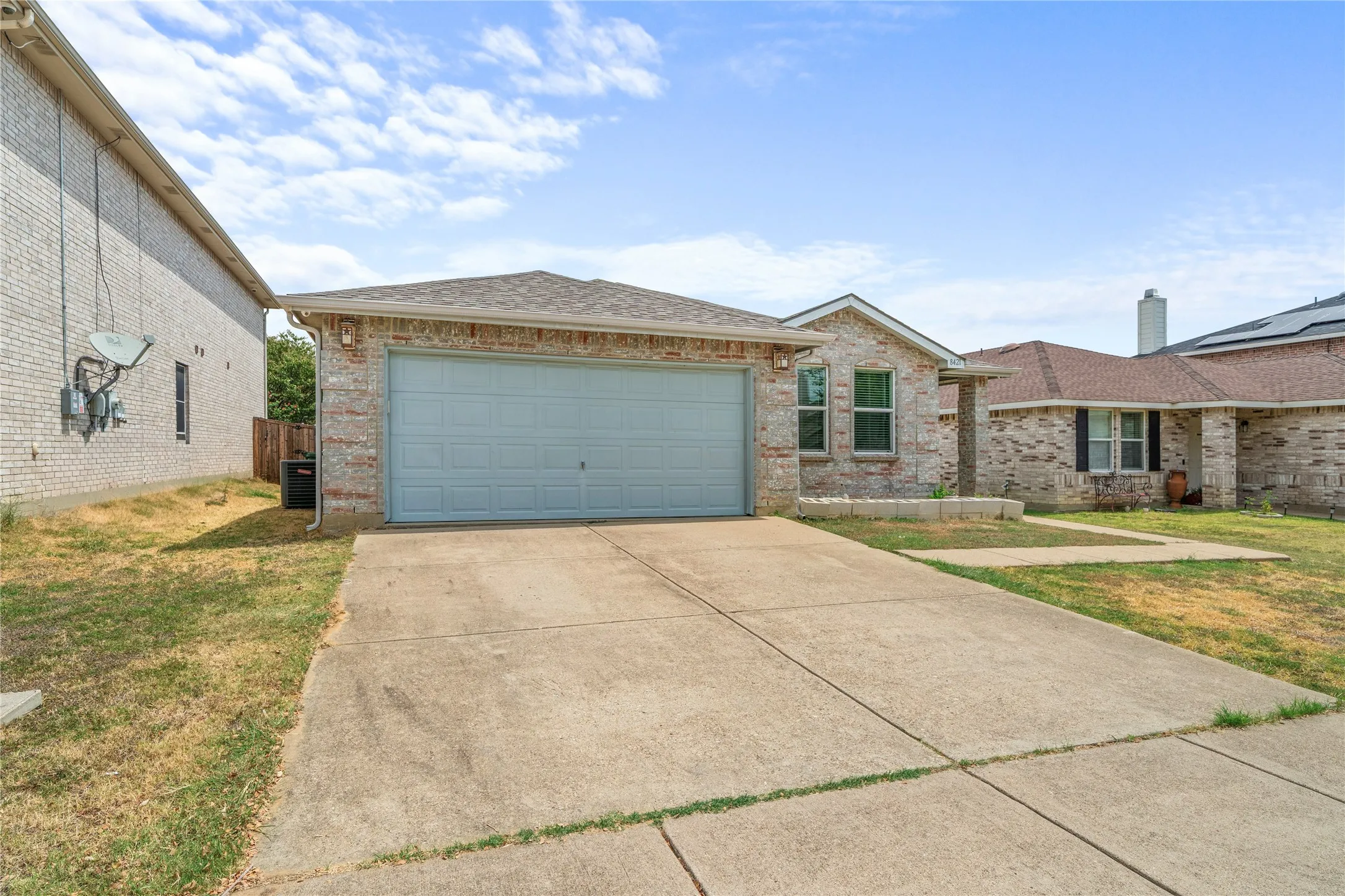 Full brick exterior, attached garage, concrete driveway, and established landscaping