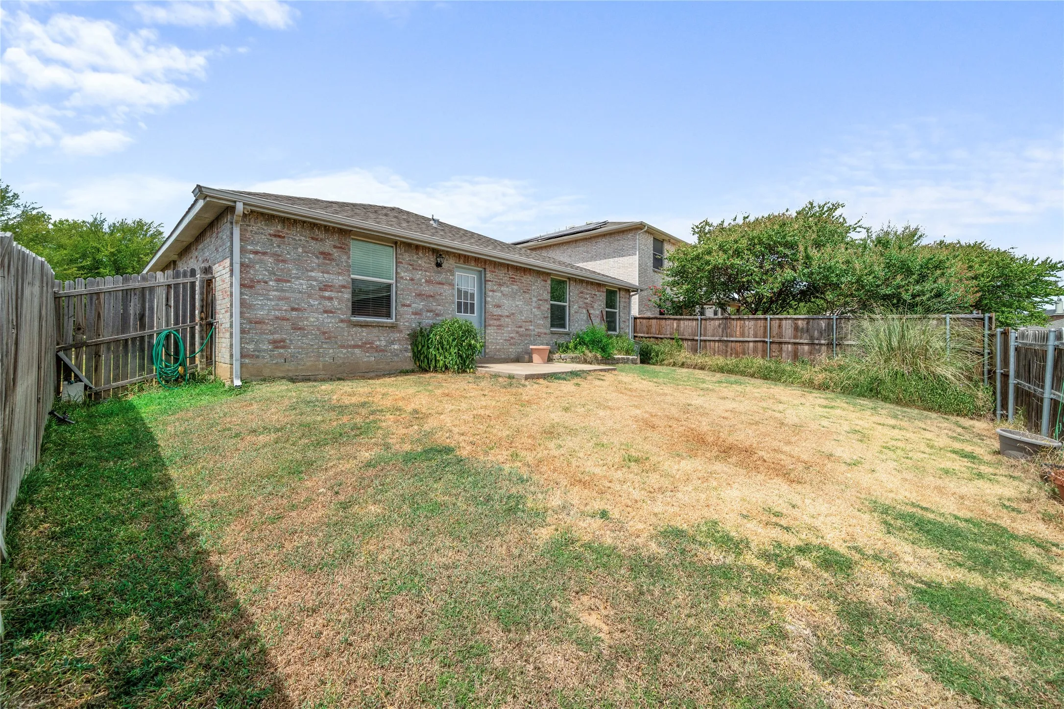 Brick exterior with a gabled roof and a wooden privacy fence