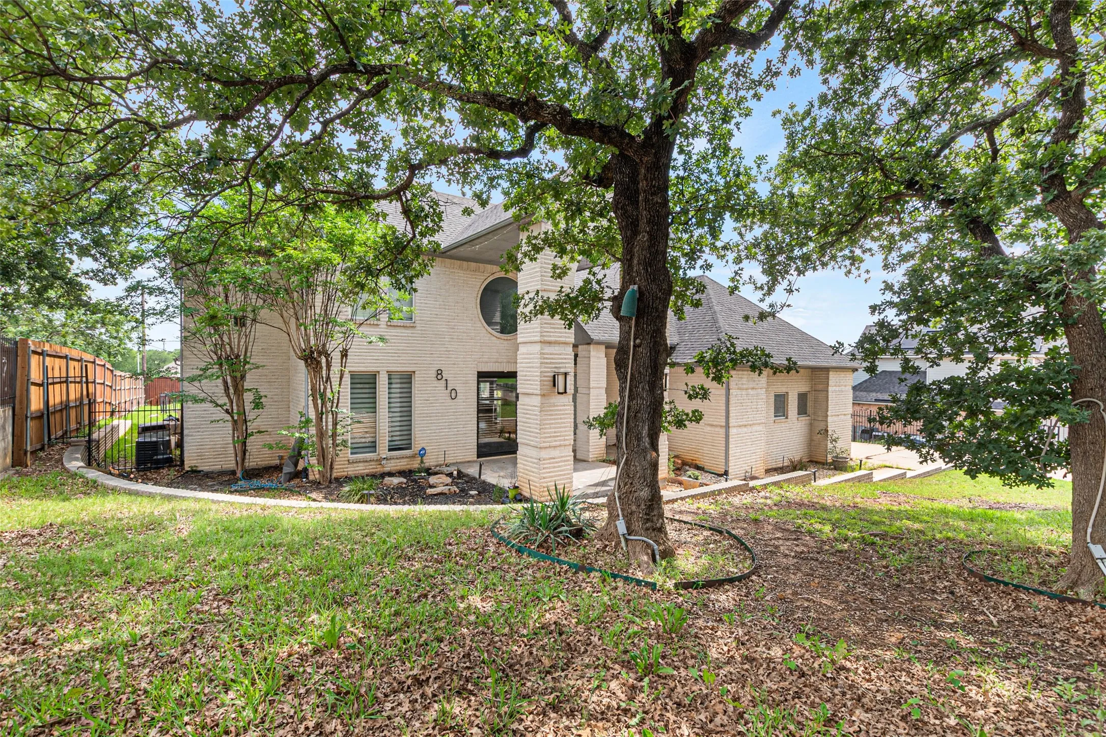 Mature oak trees provide natural shade across the expansive grounds, while the contemporary brick exterior and clean architectural lines define this residence