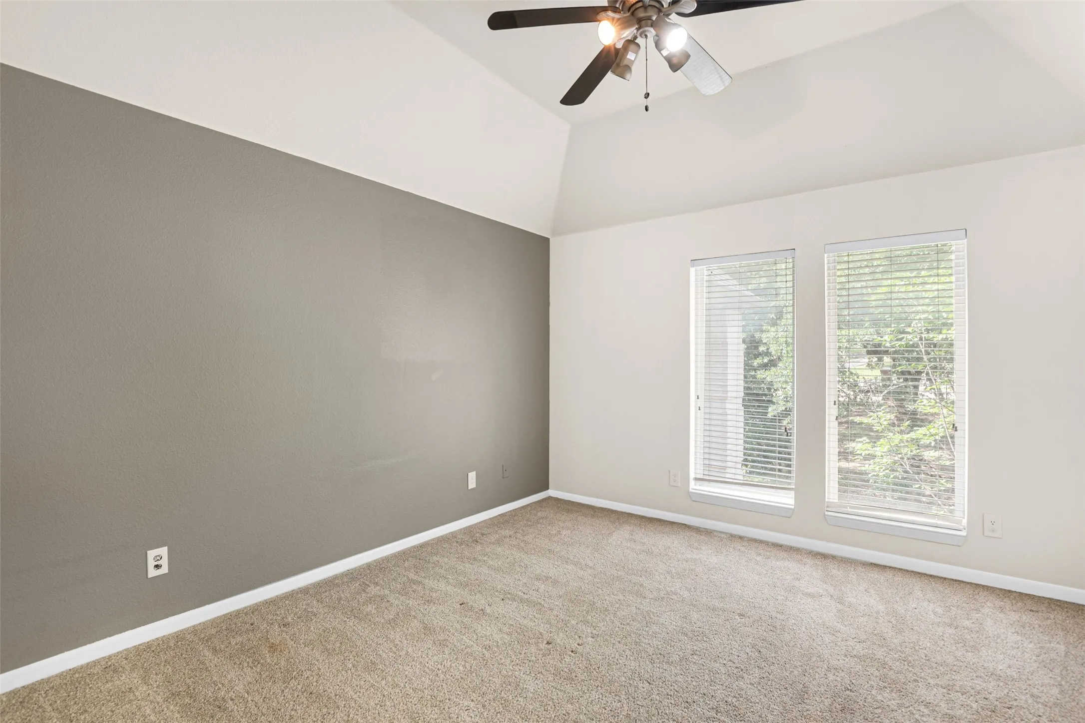 Bright and spacious bedroom with neutral wall finishes, plush carpeting, and abundant natural light from dual glass doors