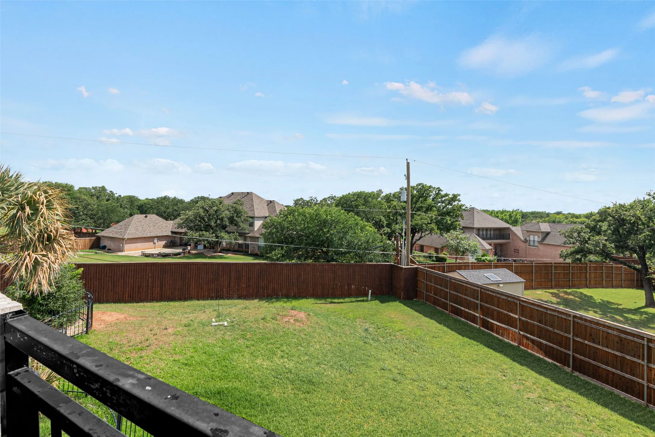 Expansive backyard with mature landscaping, manicured lawn, and wood-finish fencing
