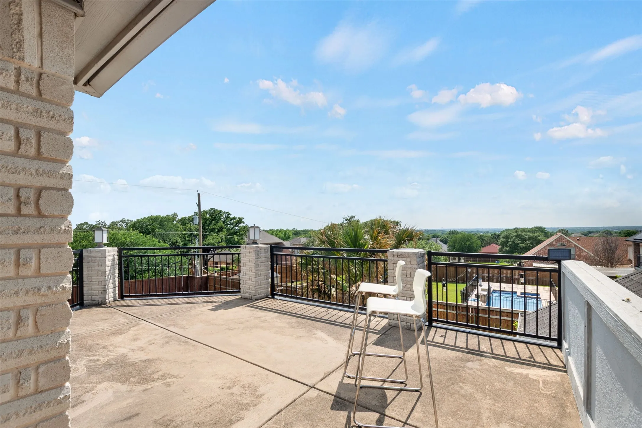 Rooftop terrace featuring expansive concrete decking, ornamental metal railing, and panoramic vistas of manicured landscaping and tree-lined grounds