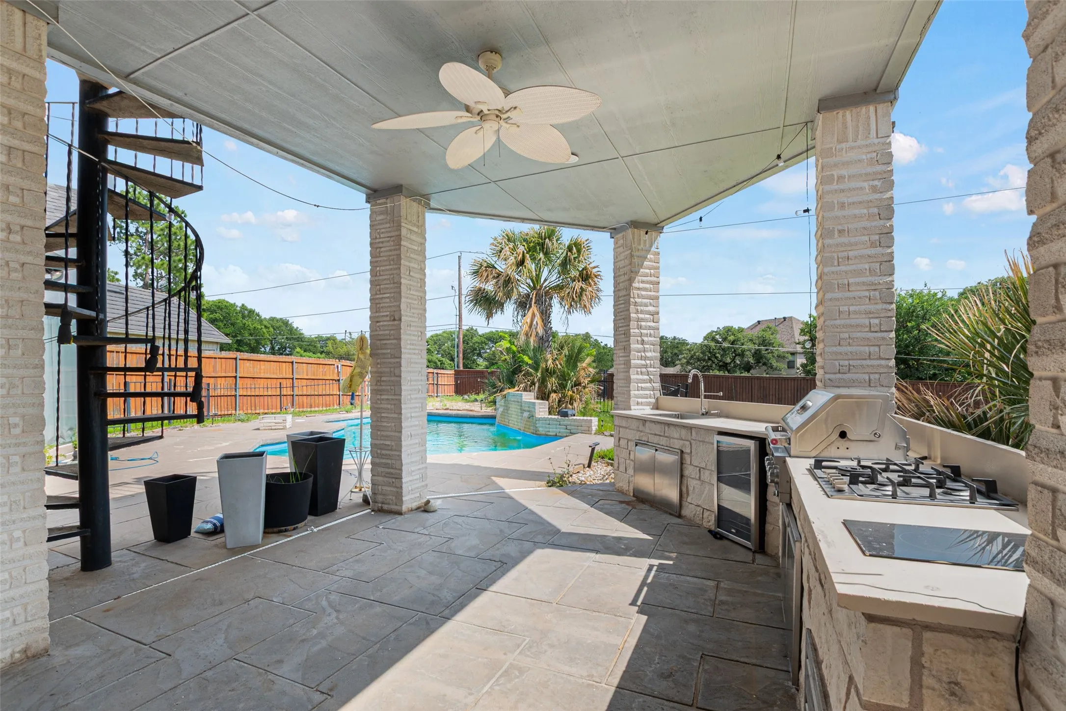 Covered outdoor entertaining space featuring composite ceiling, ceiling fan, and slate-finish pavers