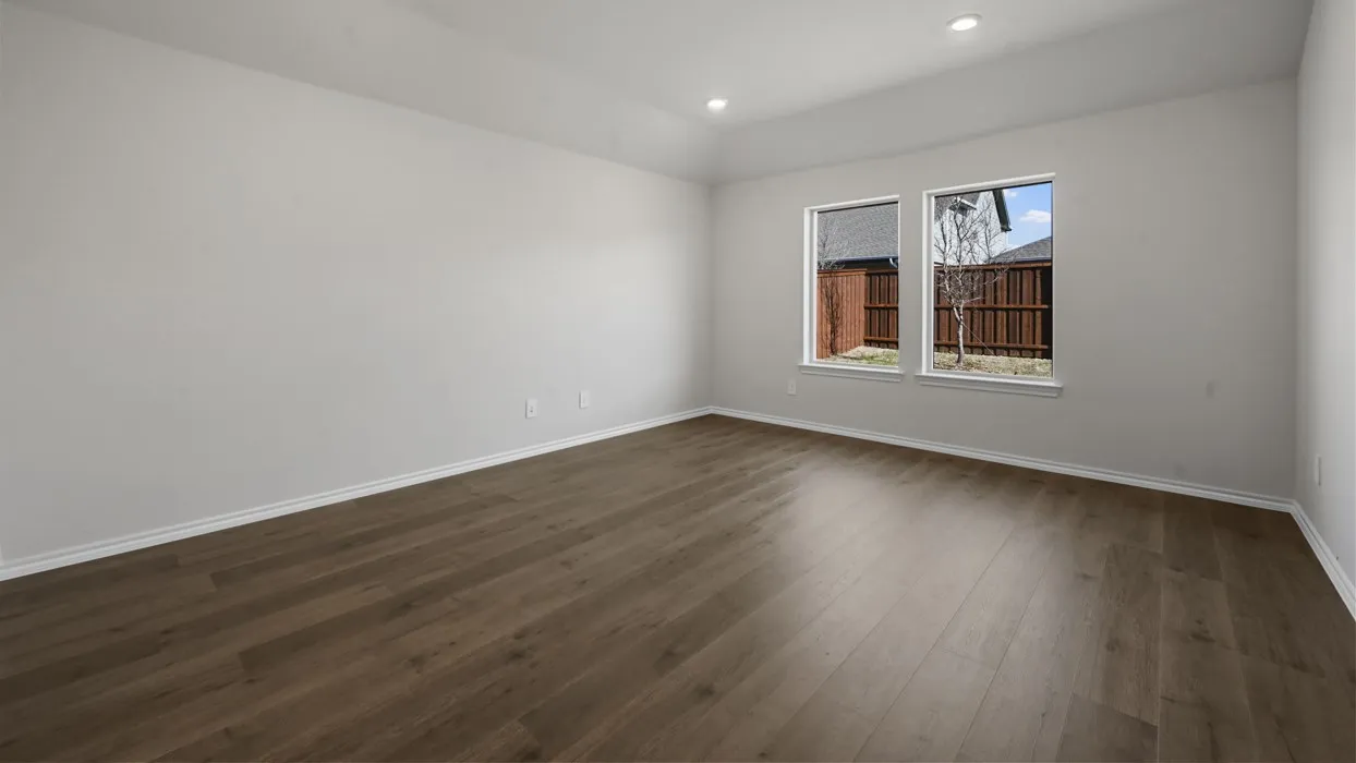 Bright, light-filled room showcasing refinished wood-finish flooring, recessed ceiling lighting, and dual windows with white trim framing natural light