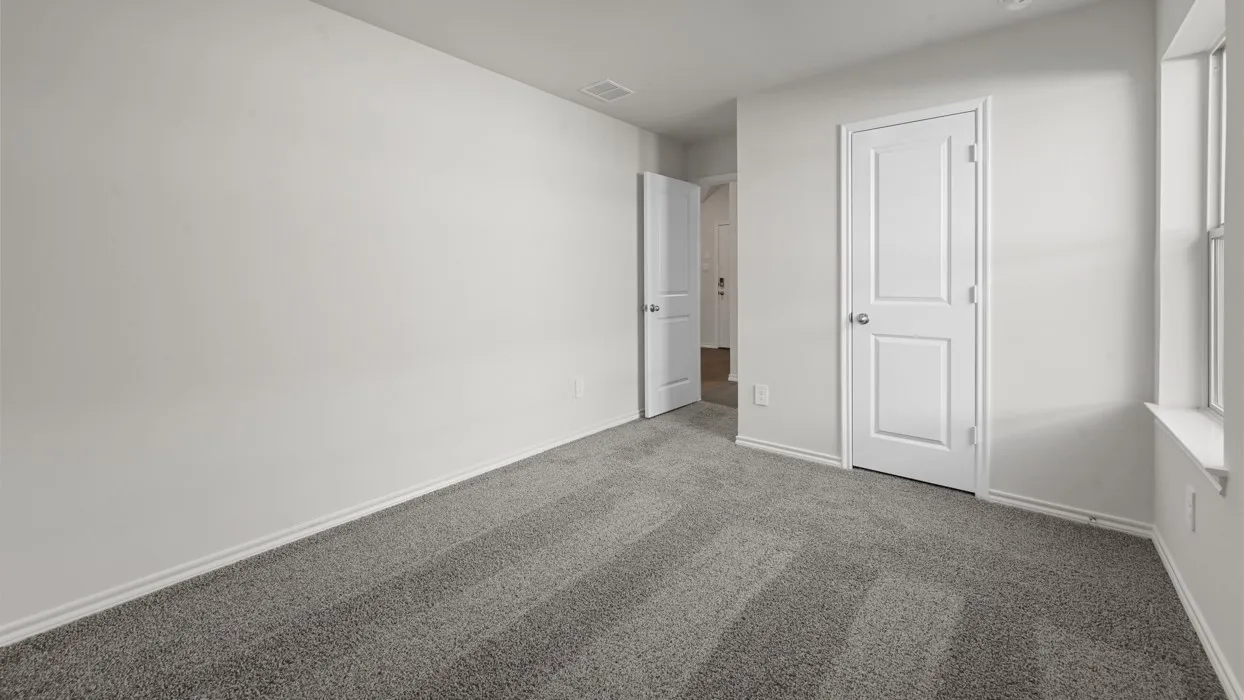 Bright secondary bedroom featuring neutral walls, dual closet storage with six-panel doors, and plush carpeting throughout