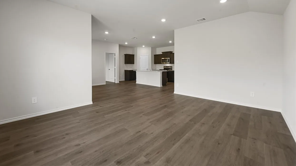 Open-concept living space featuring dark wood-finish flooring throughout, recessed ceiling lighting, and white drywall walls