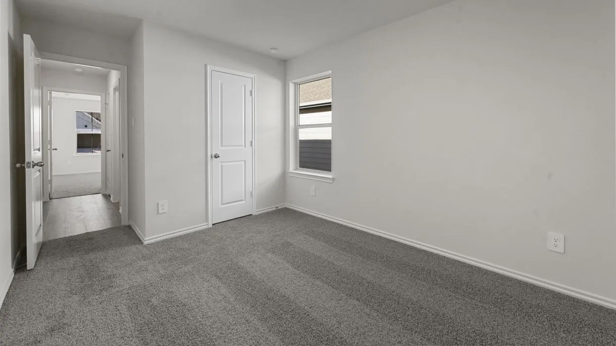 Bright, open bedroom featuring neutral wall finishes, plush carpeting, and abundant natural light from a large window