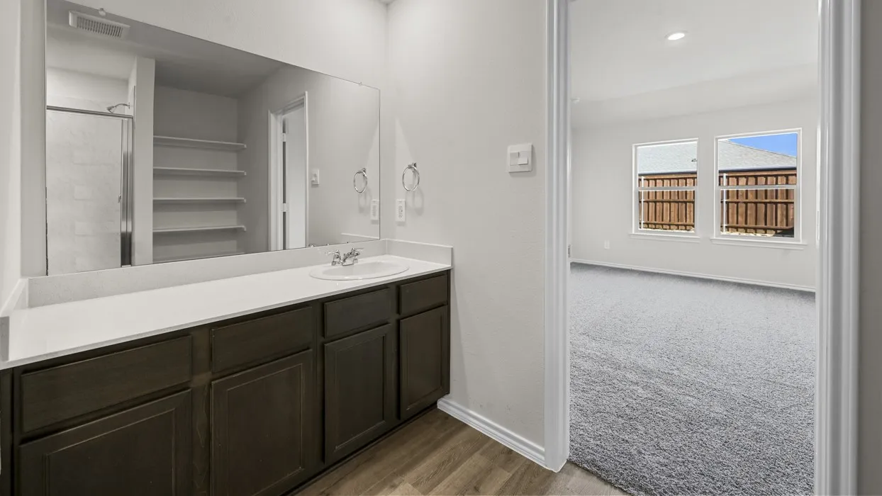 Primary bathroom featuring a dark wood vanity with an expansive white quartz countertop, chrome fixtures, and an oversized framed mirror