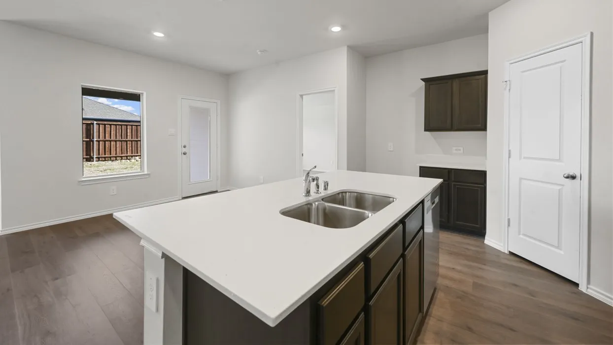 Modern kitchen featuring a dark wood cabinetry island with a stainless steel undermount sink, white quartz countertops, recessed ceiling lighting, wood-finish flooring, and white shaker-style cabinetry with dark upper storage elements