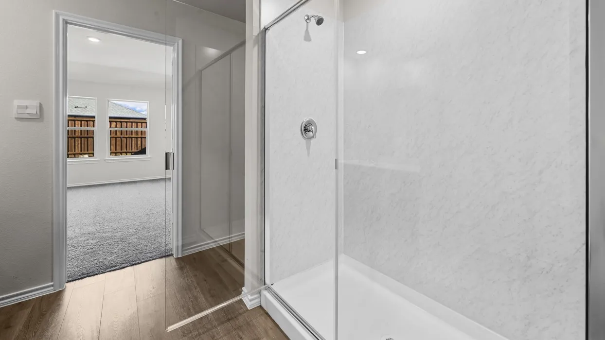 Modern primary bathroom featuring a frameless glass shower enclosure with chrome hardware, white subway tile surround, and a coordinating white soaking tub