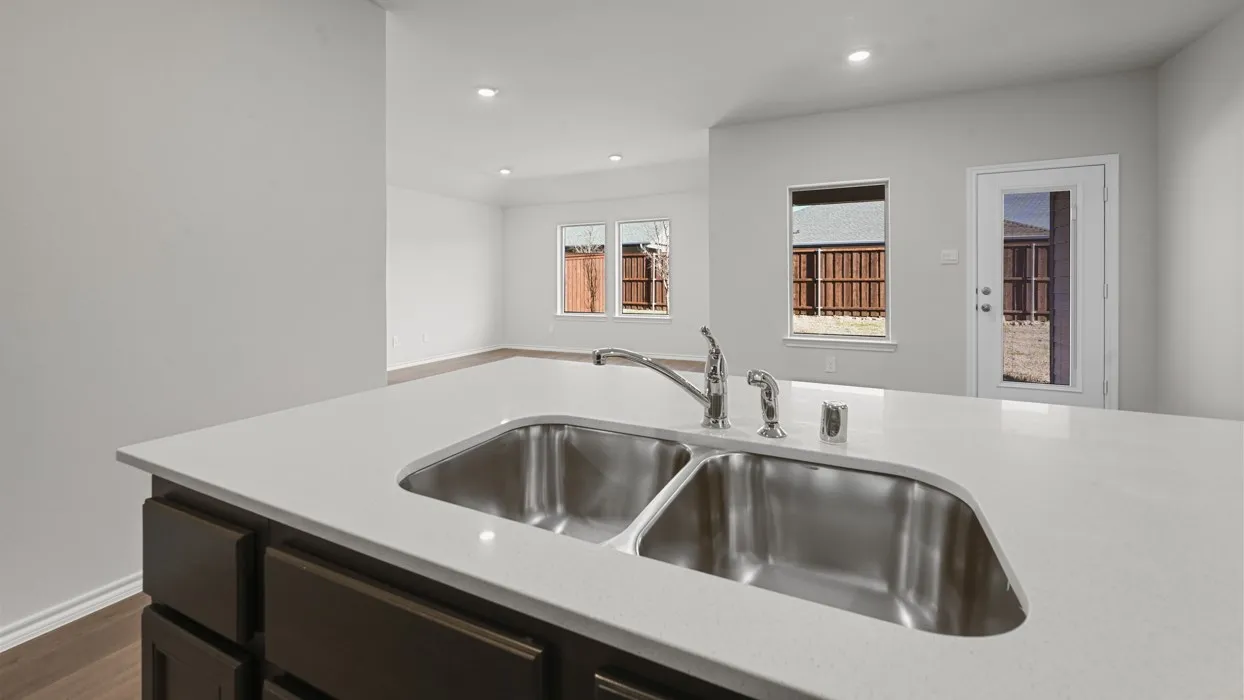 Contemporary kitchen island featuring a dual stainless steel undermount sink with polished chrome faucet, white quartz countertop, and dark cabinetry base