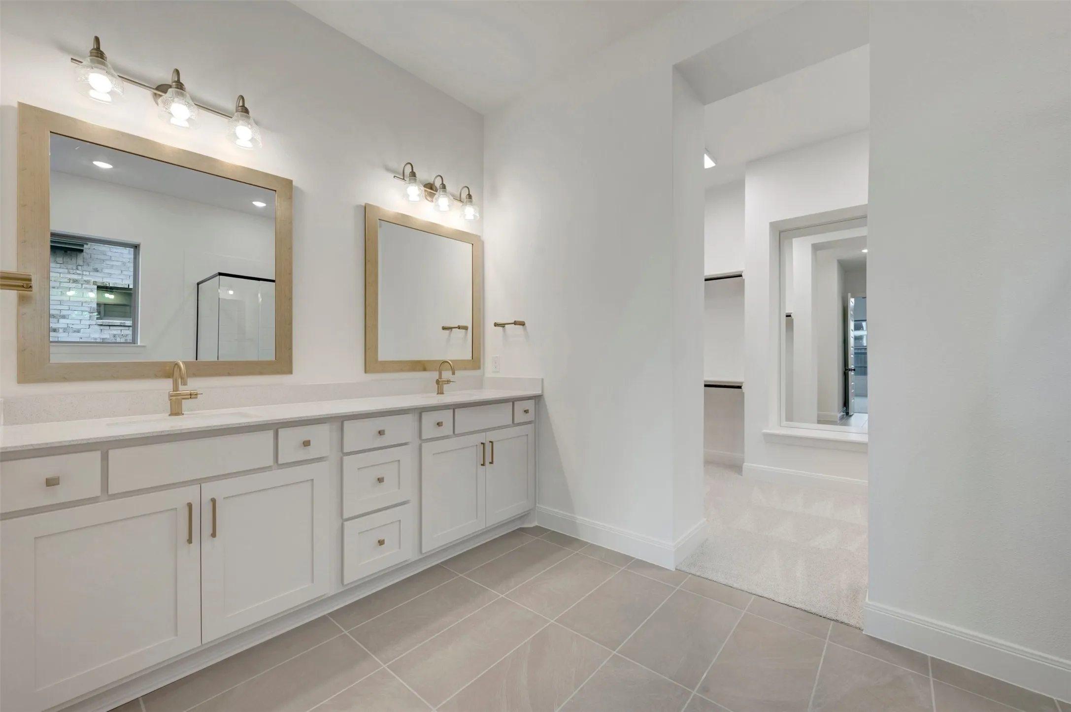 Dual vanities with white cabinetry, gold-finish fixtures, and individual mirrors