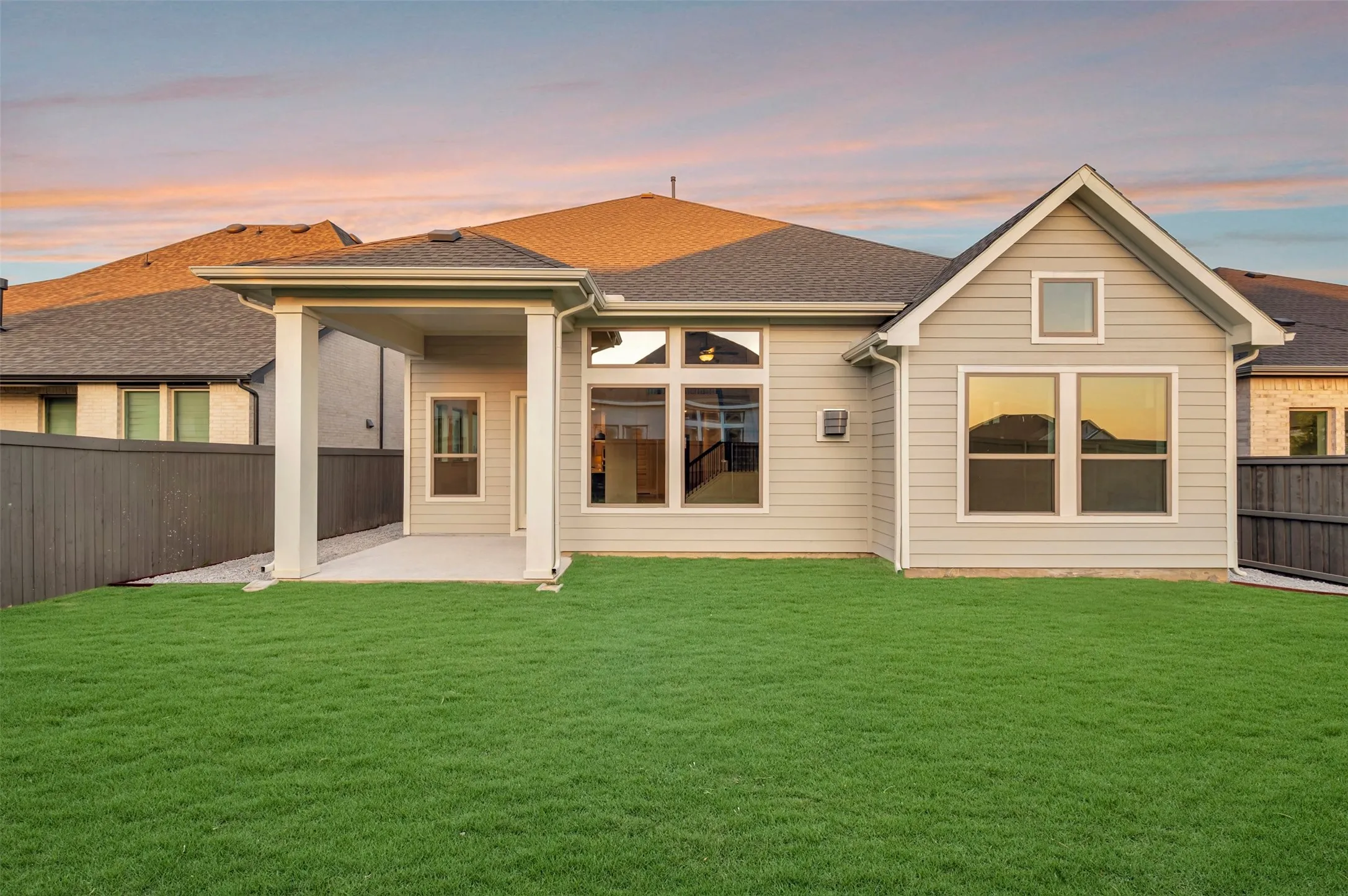 Expansive backyard featuring a covered patio, manicured lawn, and privacy fencing