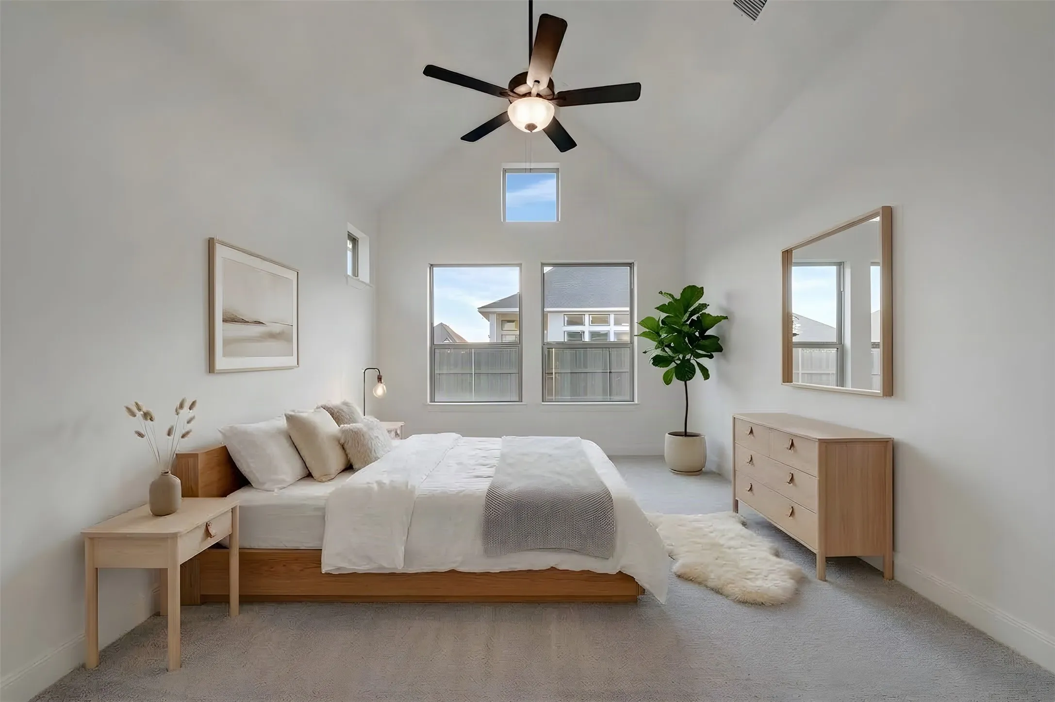 Vaulted ceiling with an installed ceiling fan, carpeted flooring, and multiple windows providing natural light