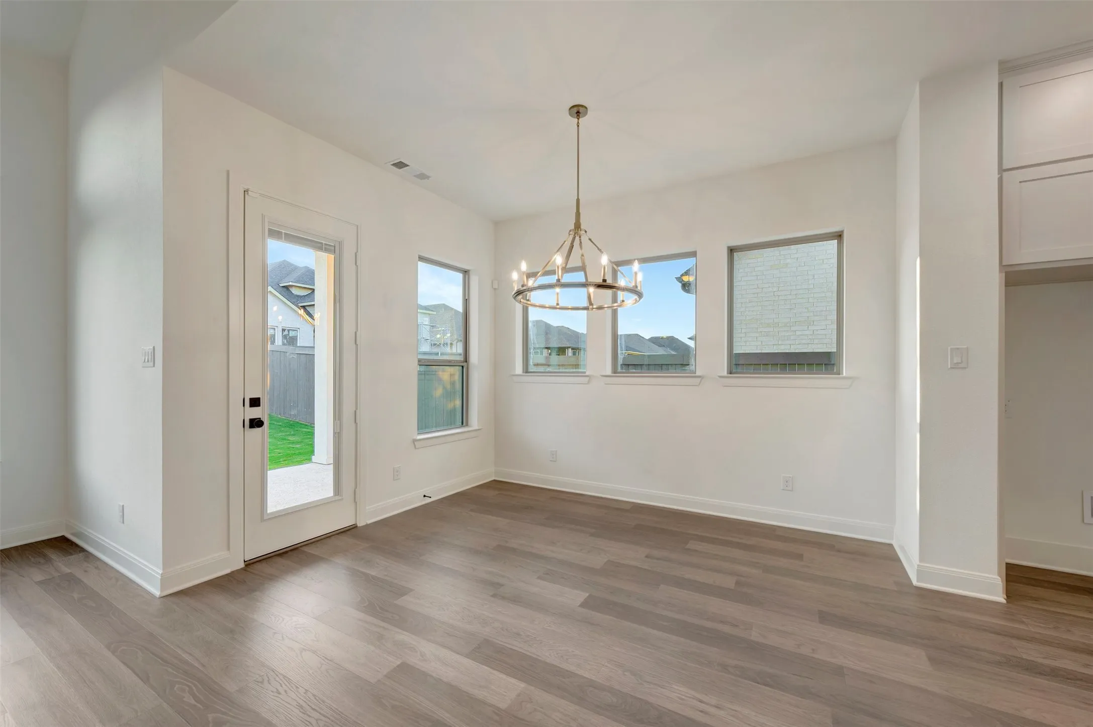 Wood-finish flooring, multiple windows, built-in cabinetry, and a contemporary chandelier