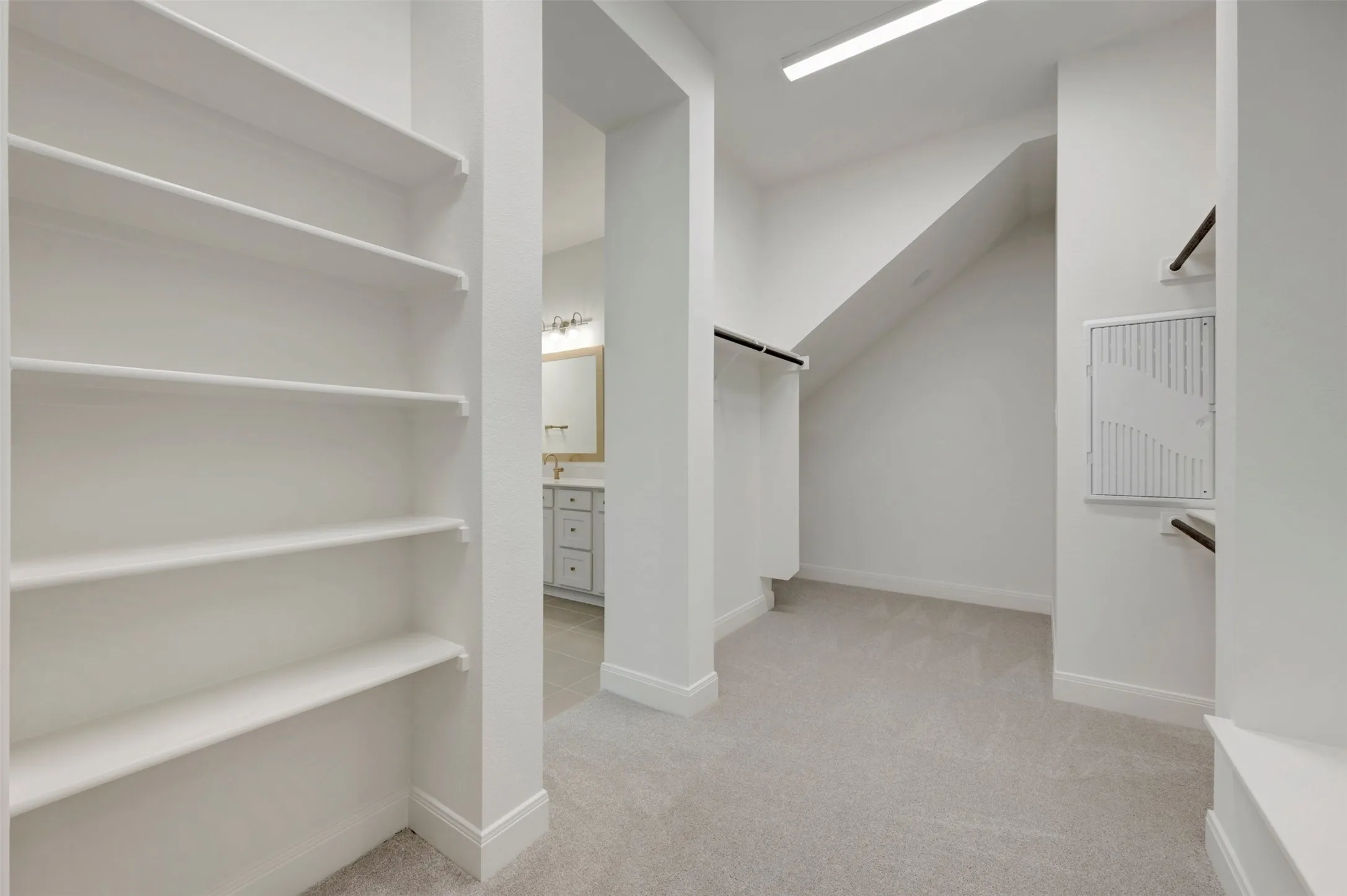 Carpeted closet with built-in shelving, hanging rods, and recessed lighting