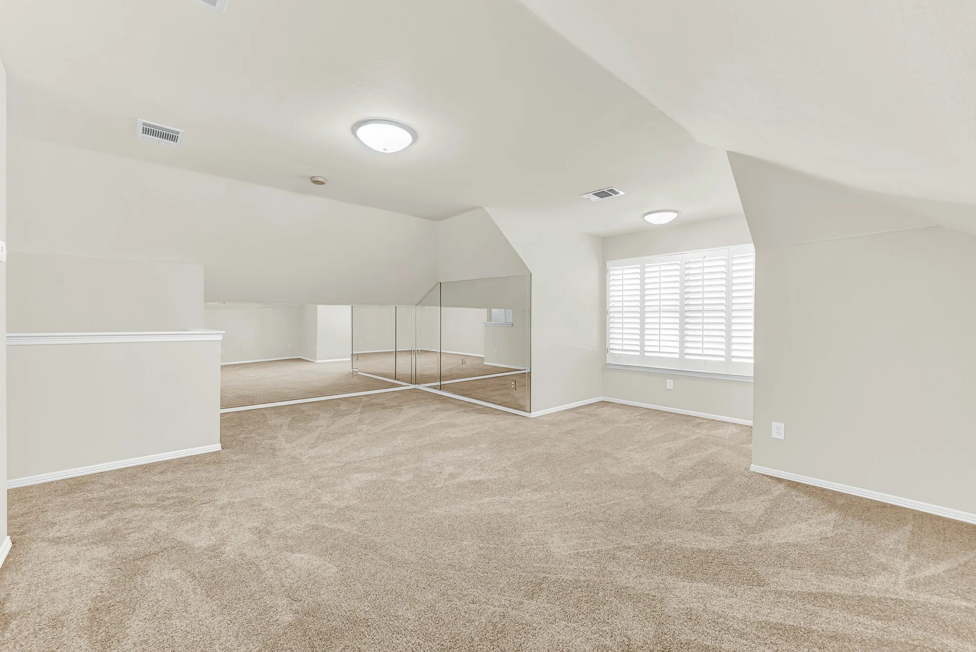 A wide angle highlights the unique angled ceilings, expansive plush carpeting, and the mirrored wall that amplifies the natural light throughout the second floor. You will love setting up a game room or play area where kids and guests can gather for fun weekend afternoons.