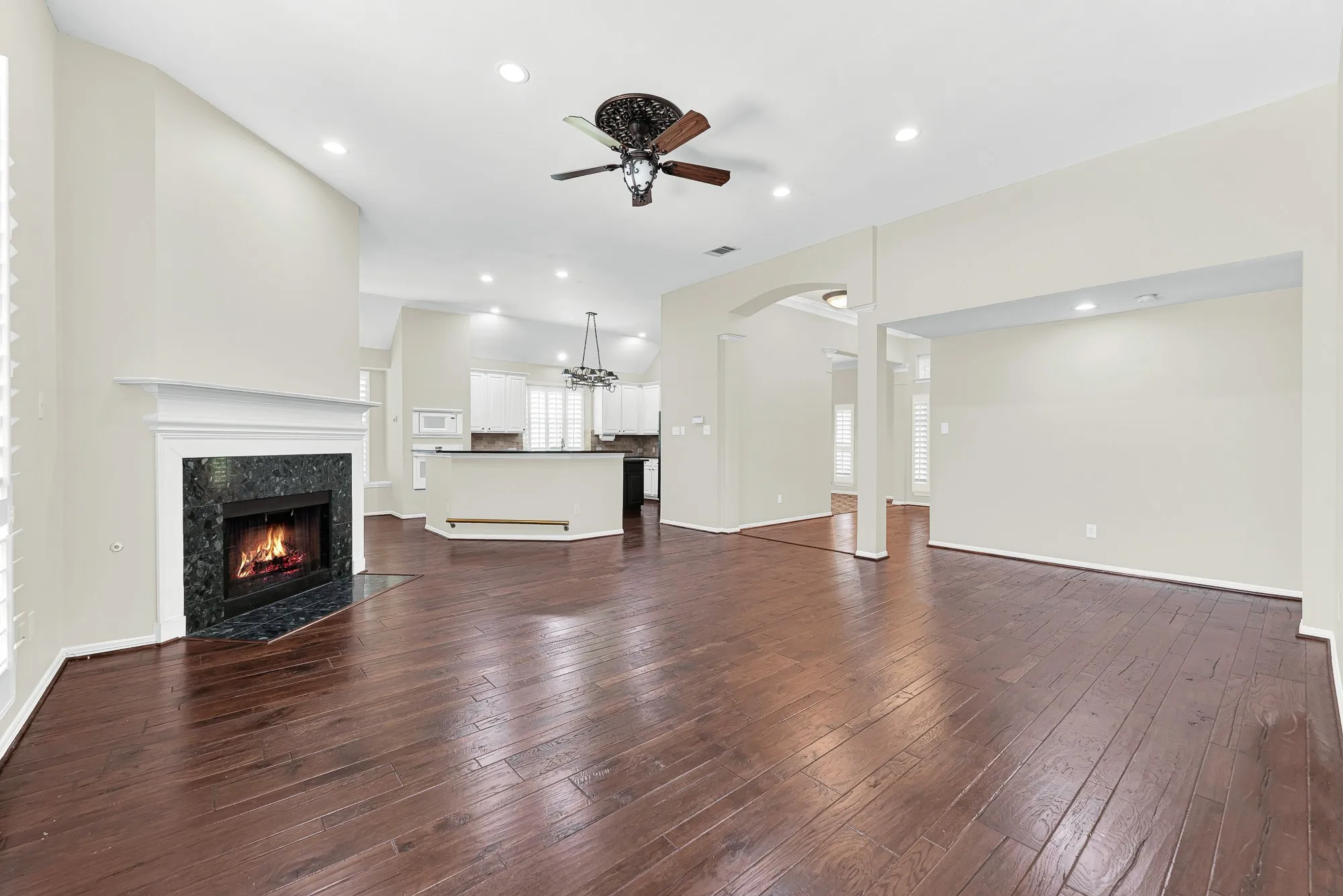 Captured from the window wall, this view emphasizes the impressive high ceilings, central fireplace, and wide doorways connecting adjoining spaces. The generous layout offers plenty of room for everyday family fun and smooth movement during holiday celebrations.