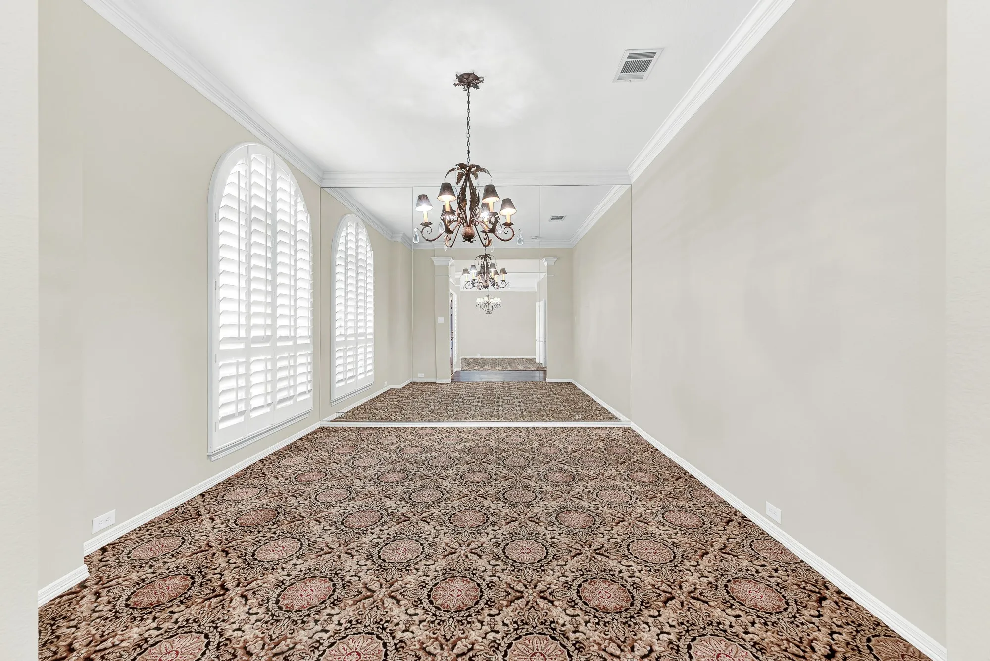 A classic chandelier, soaring ceilings, and a dramatic mirrored wall amplify the natural light across this versatile formal living area. It offers a wonderfully cozy environment to relax with a good book or host intimate evening conversations after a family dinner.