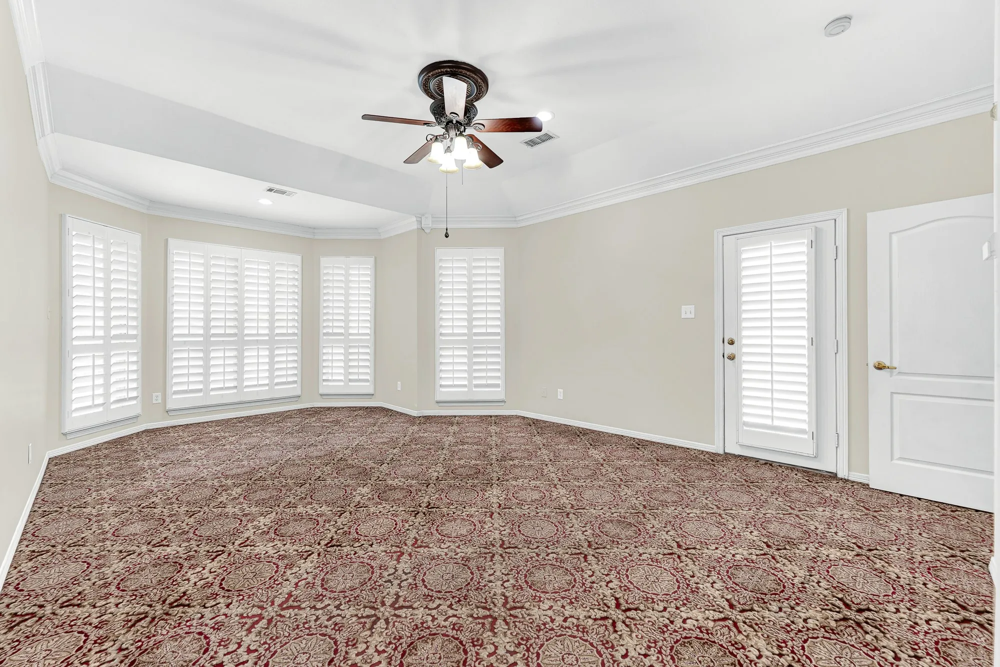 Framed by plantation shutters along a bay wall, this spacious angle showcases a private exterior door that opens out toward the patio area. Imagine waking up slow on peaceful weekend mornings and stepping right outside for fresh air and morning sun.