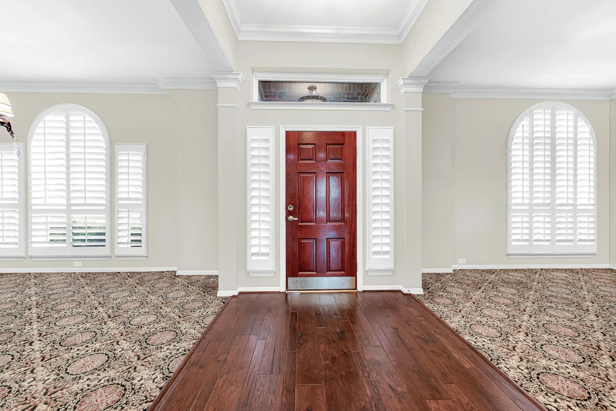 Rich hardwood flooring creates a welcoming grand entrance, flanked by arched windows with plantation shutters and balanced openings to formal spaces. You will love greeting your guests in this bright foyer that sets a warm, sophisticated tone the second anyone walks through the front door.