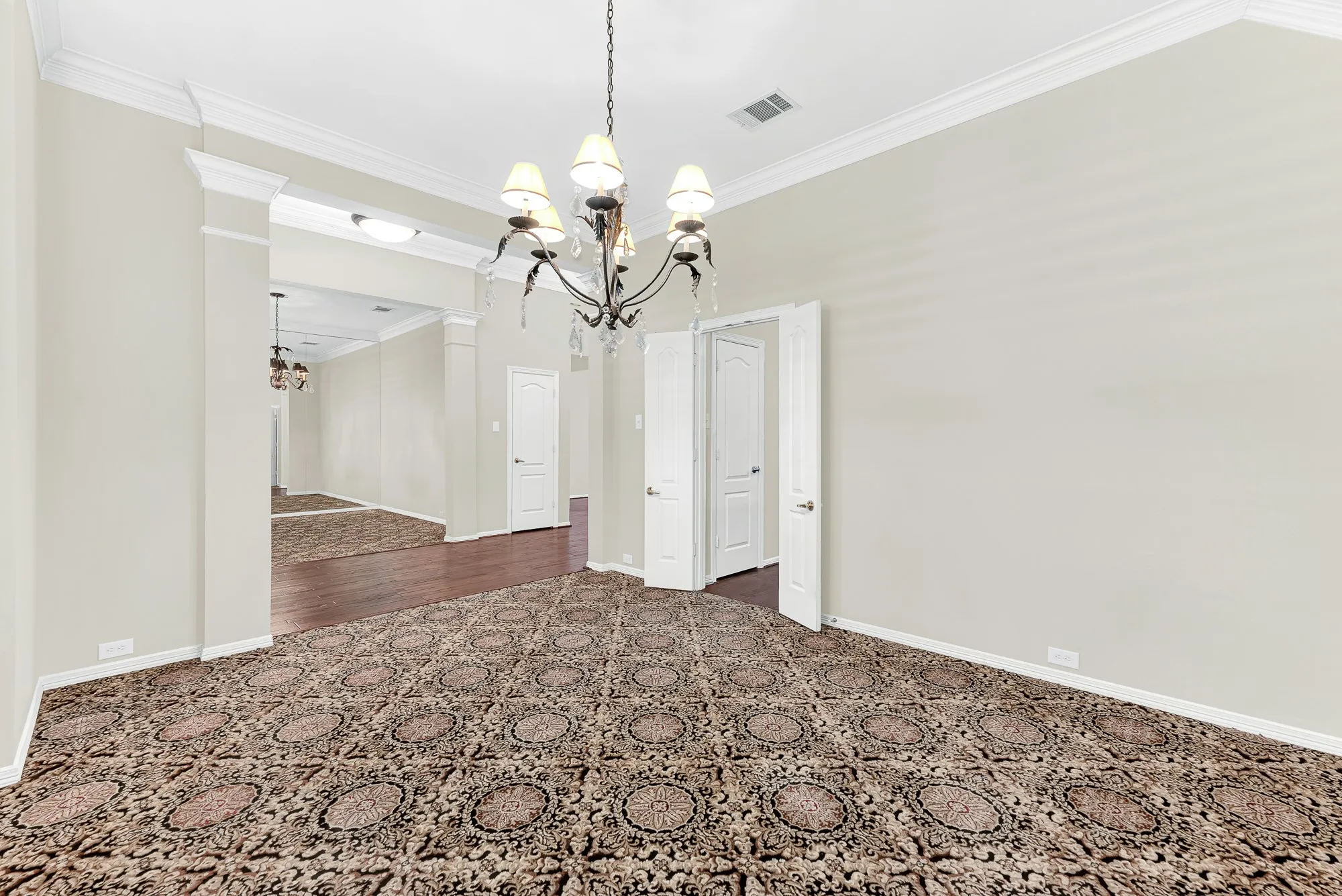 Framed by double doors and refined crown molding, this view highlights the easy flow into adjoining living space, kitchen and foyer. Imagine flowing effortlessly between cocktail hour and dinner while entertaining friends in style.