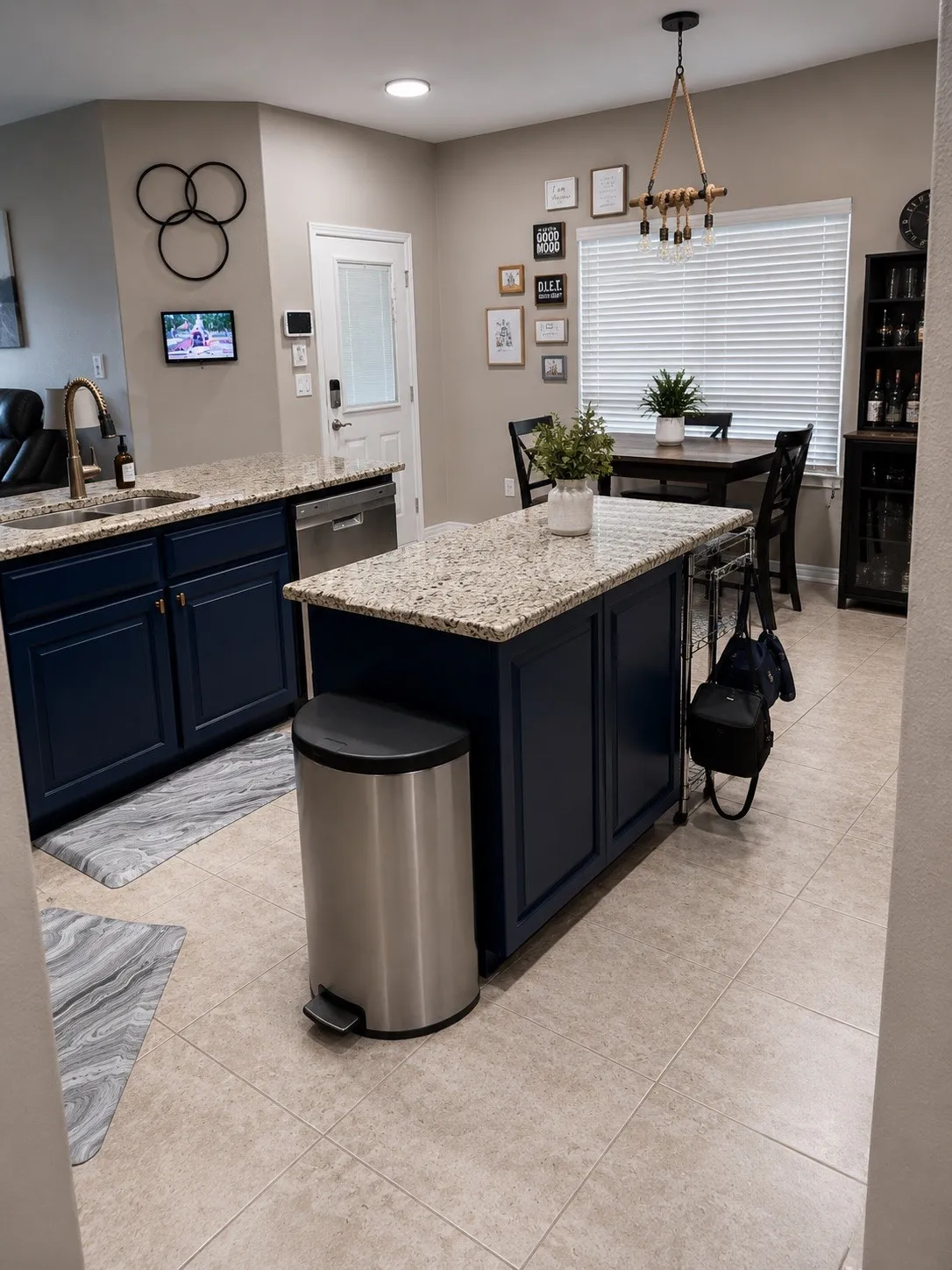 Kitchen featuring an island, granite countertops, dark blue cabinetry, tile flooring, and a built-in dishwasher