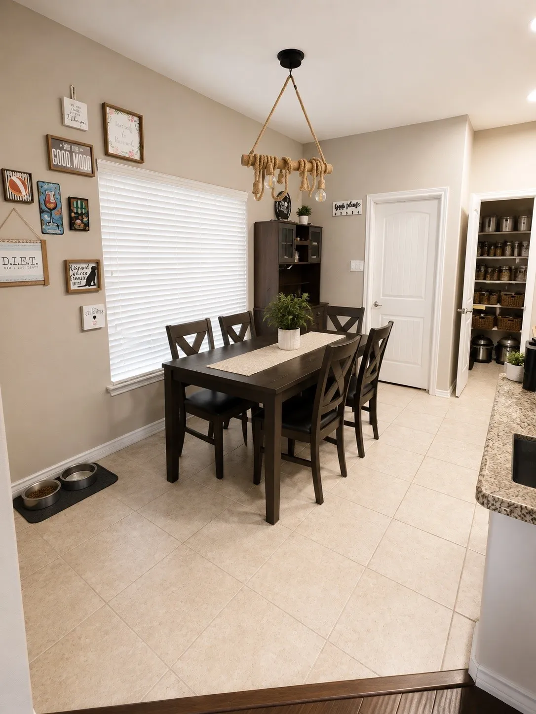 Dining area featuring light-colored tile flooring, a window with blinds, and a pantry with built-in shelving