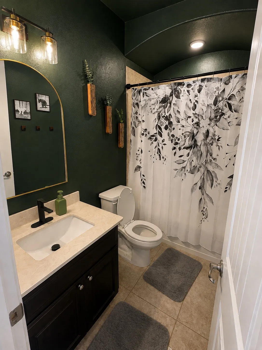 Dark-painted walls and arched ceiling, wood-finish vanity with a light-toned countertop, integrated sink, and black faucet, and tiled flooring