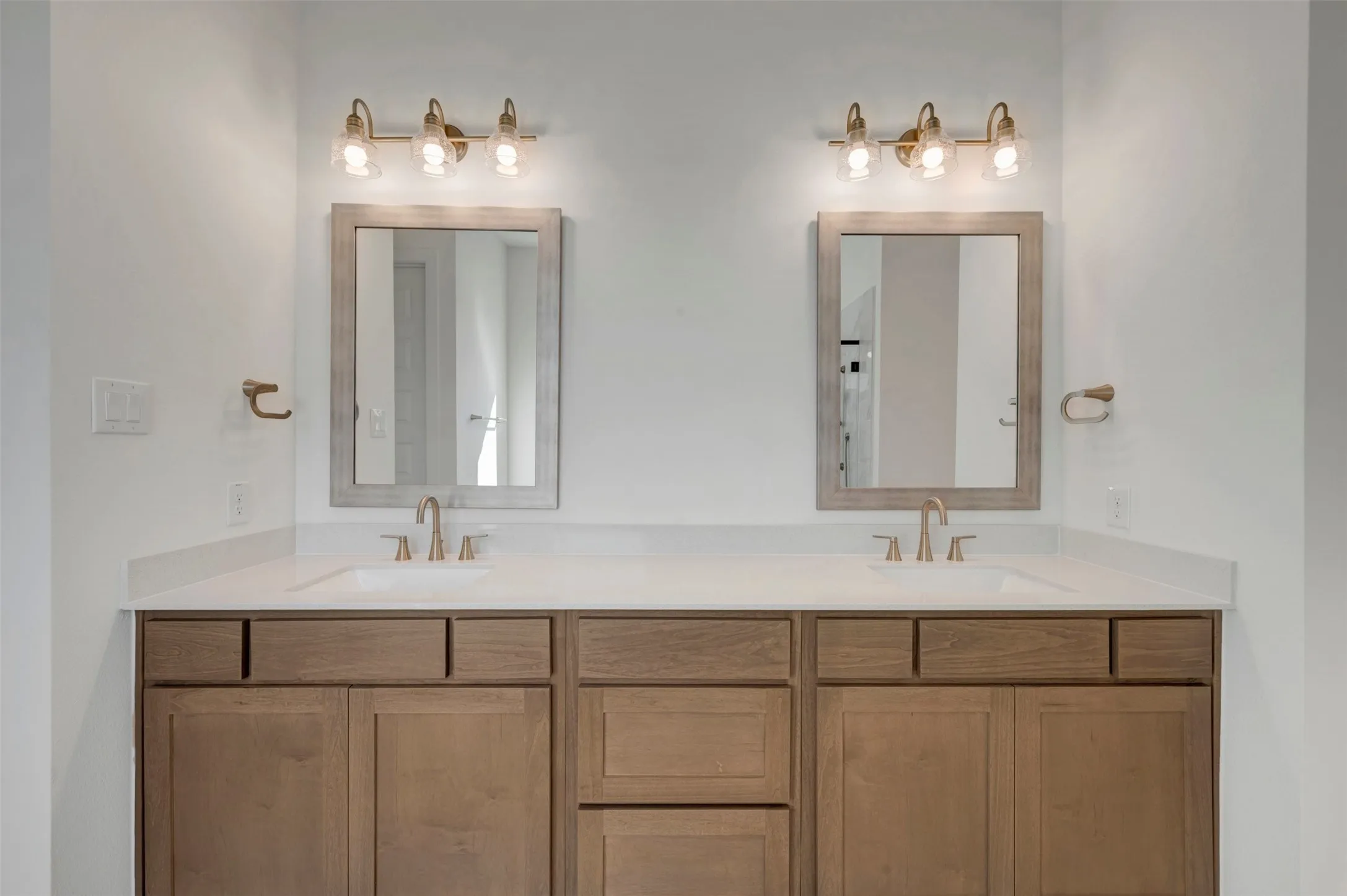 Dual vanity featuring wood-finish cabinetry, white countertop, two undermount sinks, and two framed mirrors