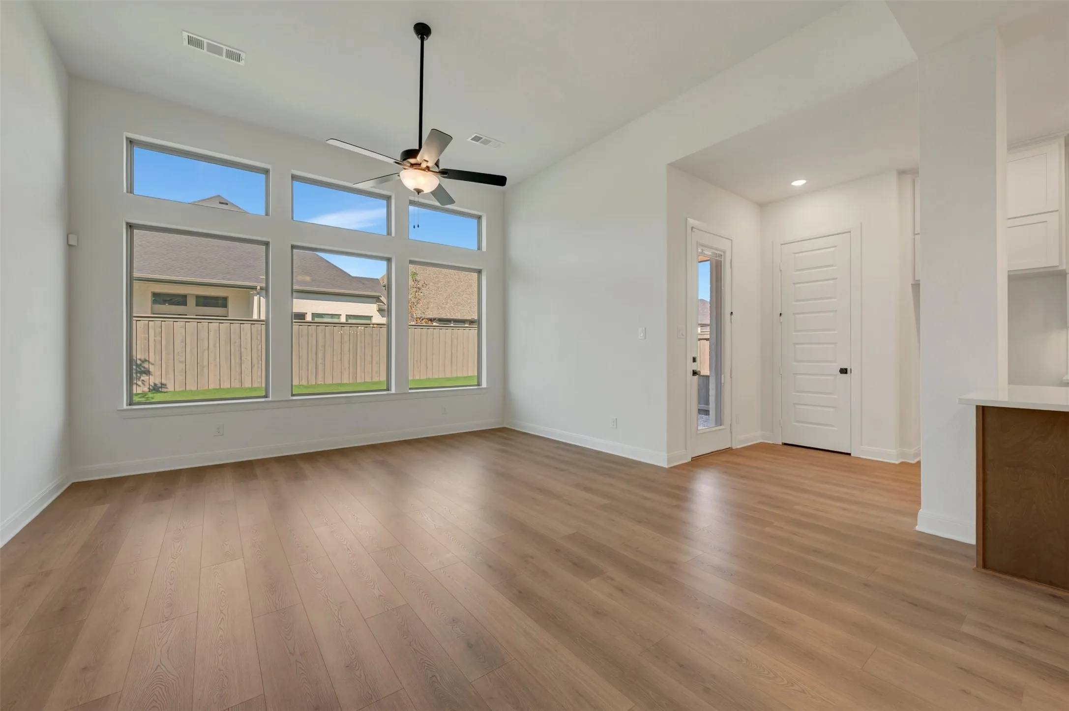 Vaulted ceiling, wood-finish flooring, contemporary ceiling fan, expansive windows, recessed lighting