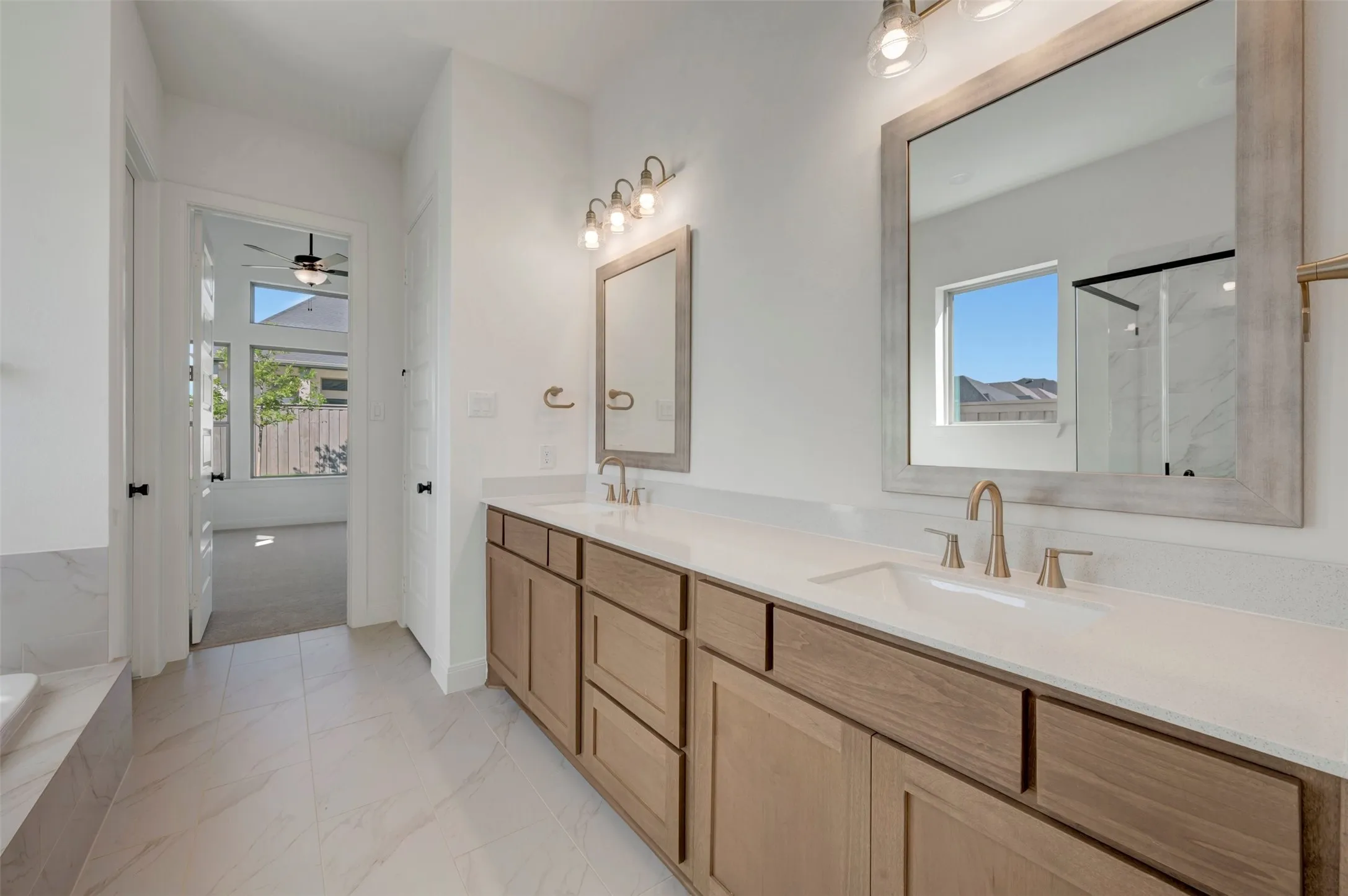 Double vanity with stone-finish countertops, undermount sinks, and brushed gold fixtures