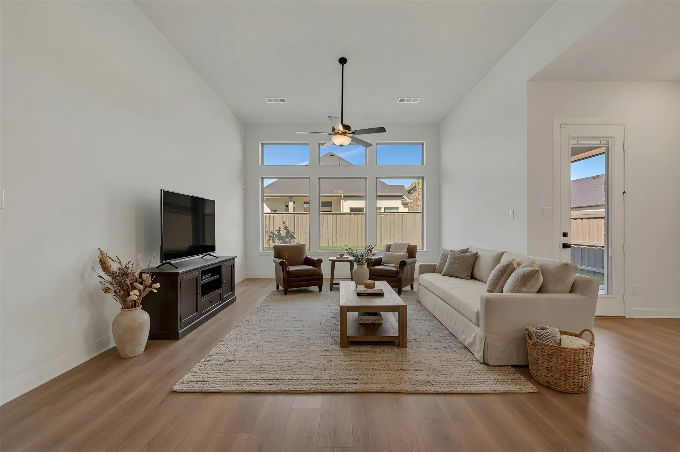 High ceilings enhance this living area featuring wood-finish flooring and a ceiling fan