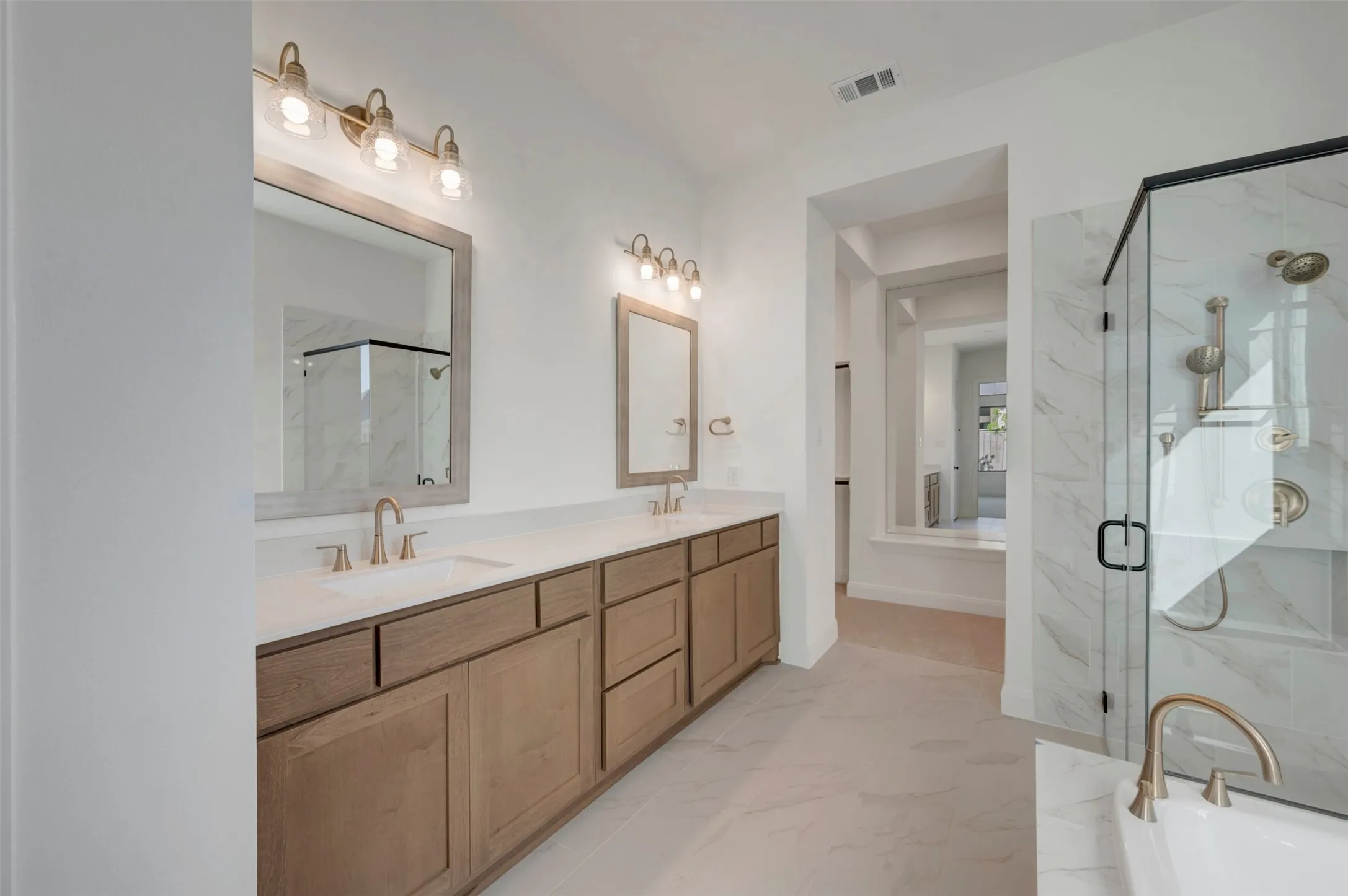 Dual vanity with undermount sinks, quartz countertop, wood-finish cabinetry, and framed mirrors