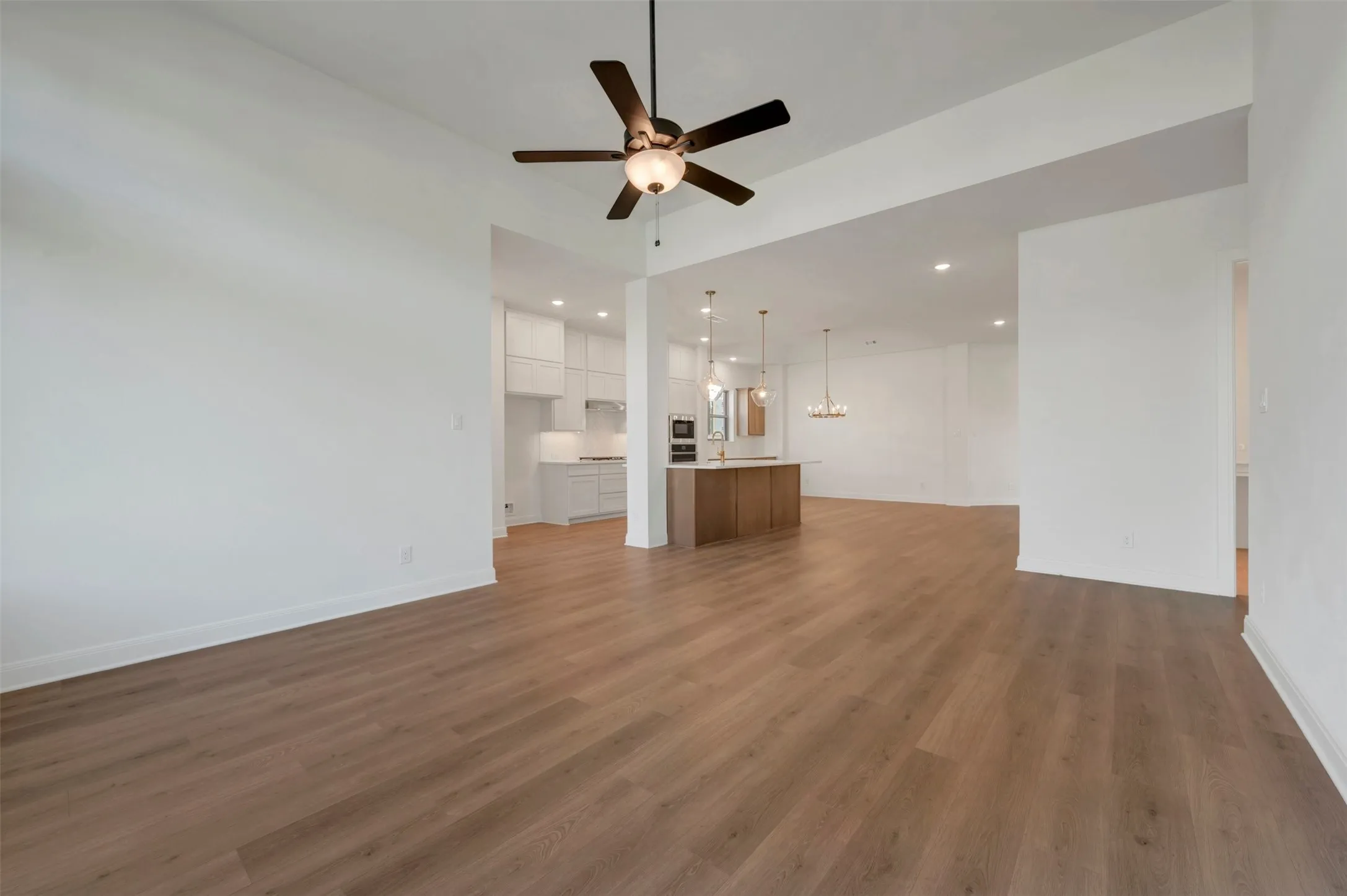 Open-concept living area featuring wood-finish flooring, a contemporary ceiling fan, and recessed lighting