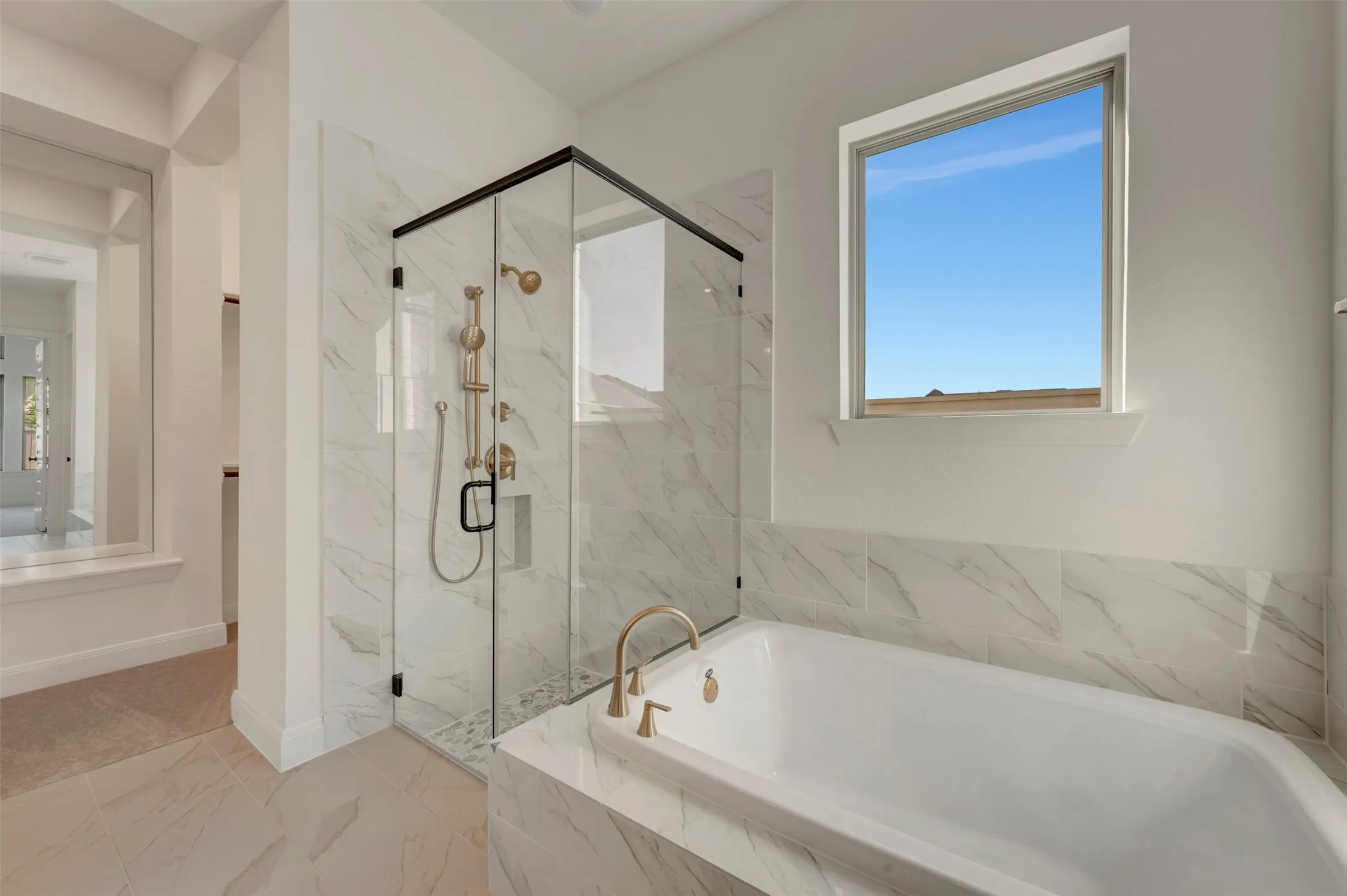Spacious bathroom featuring a built-in soaking tub, walk-in glass shower enclosure, and large window