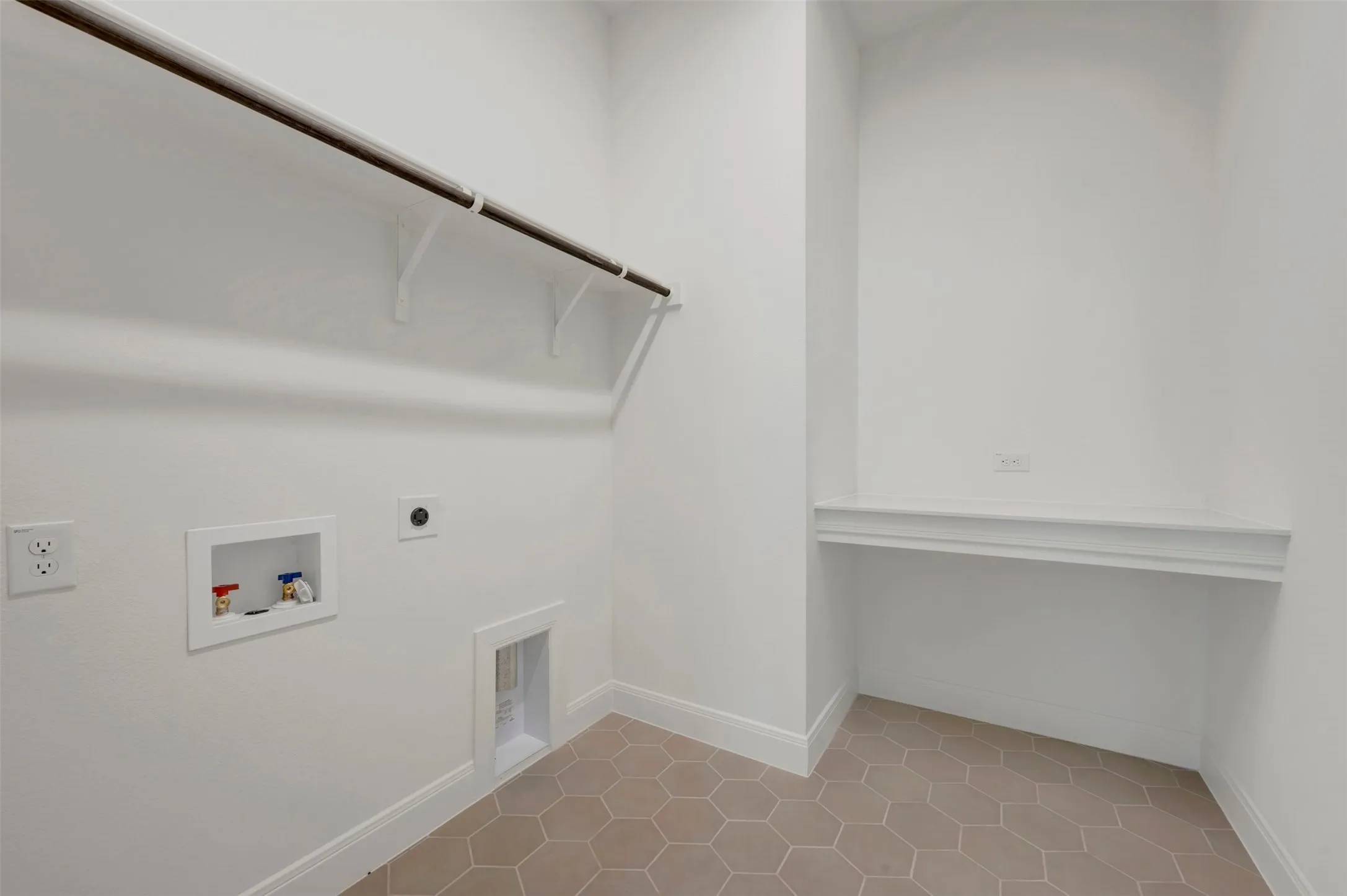 Hexagonal tile flooring, built-in shelving, mounted clothes rod, and appliance hookups