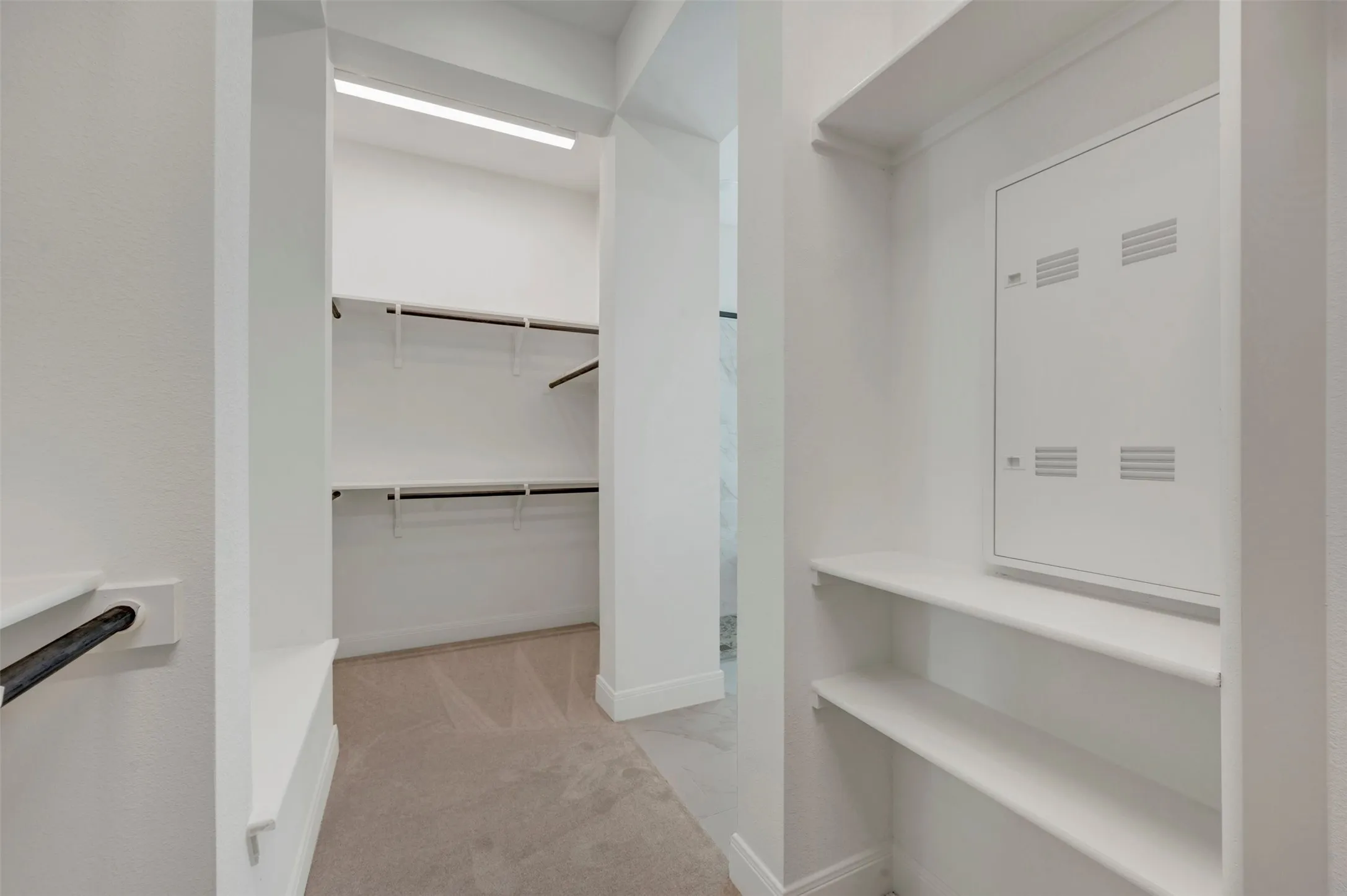 Walk-in closet with carpet flooring, built-in shelving, and hanging rods