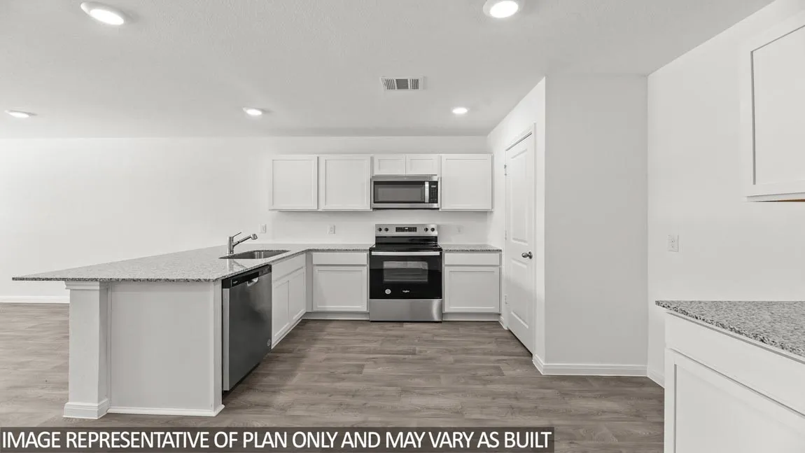 Modern kitchen featuring white cabinetry, stainless steel appliances including a built-in oven and microwave, granite countertops, and a large island with wood-finish flooring throughout the open layout