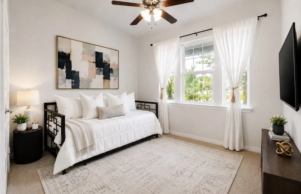 Bright secondary bedroom featuring a ceiling fan with integrated lighting, large multi-pane windows with sheer curtains, neutral wood-finish flooring, and a neutral area rug. Virtual Staged Decor