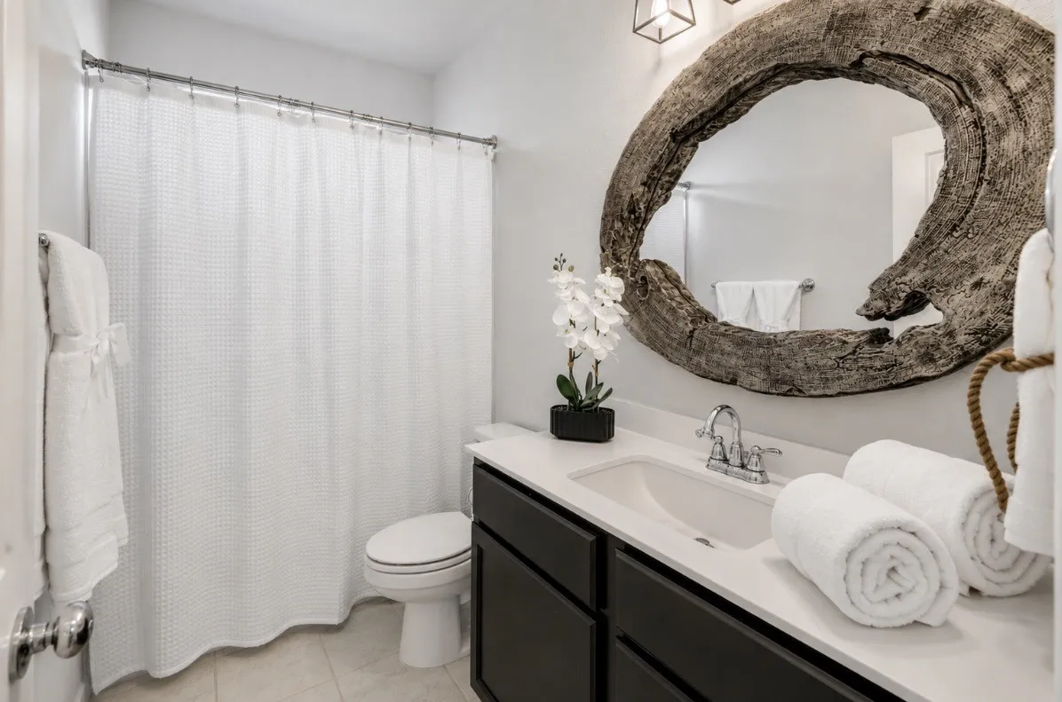Spa-inspired bathroom featuring a dark vanity with white quartz countertop, chrome faucet fixtures, and abundant counter space