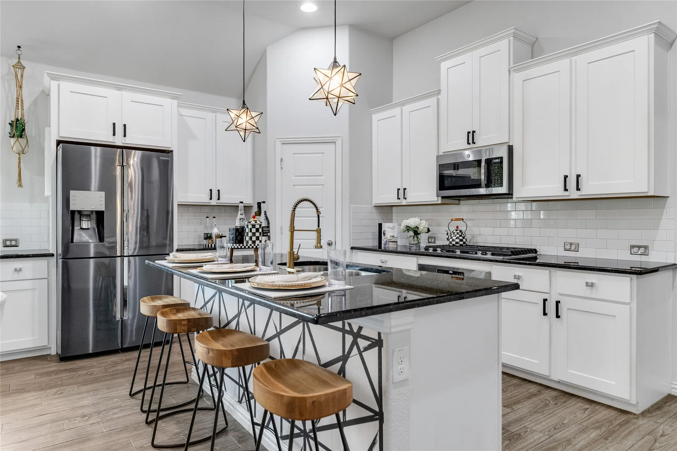 Kitchen featuring a spacious island with seating, white shaker cabinetry, stainless steel appliances, a subway tile backsplash, and dark countertops