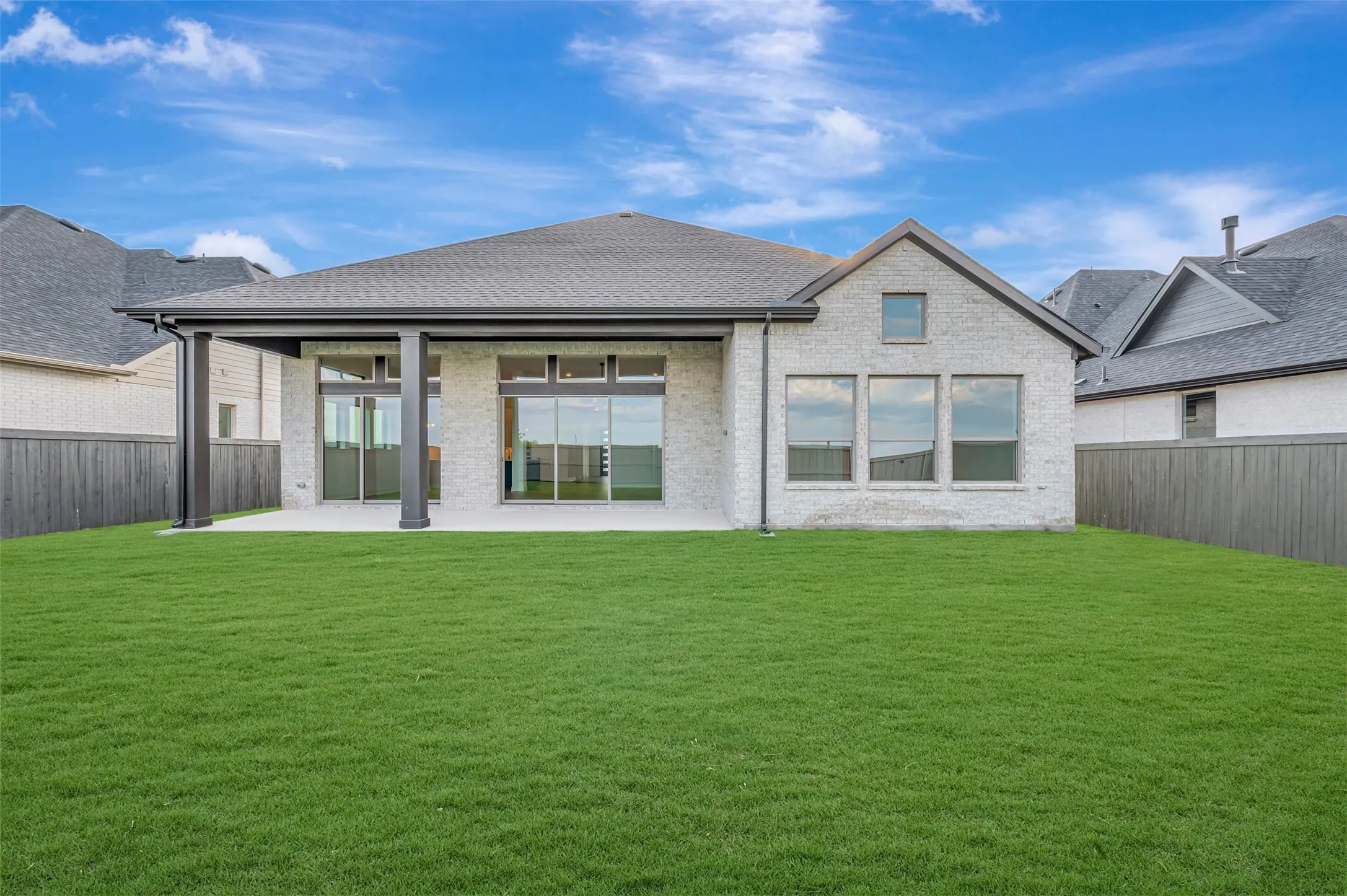 Modern residence showcasing a light-finished brick exterior with large multi-pane windows, a covered entry portico with columns, and a hipped roofline