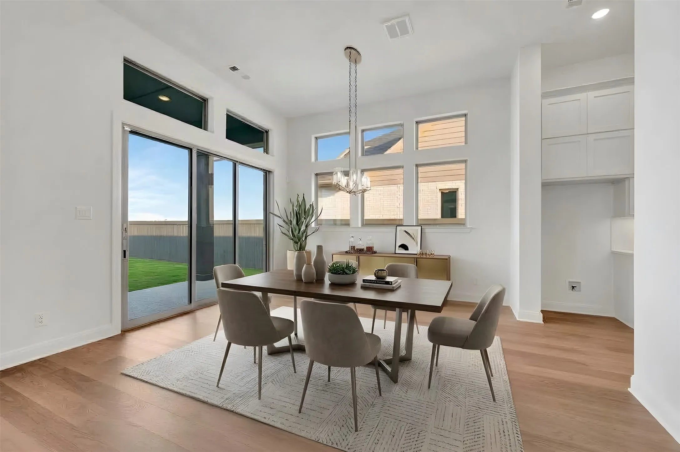 High ceilings with transom windows, wood-finish flooring, sliding glass doors, built-in cabinetry, and a tiered chandelier