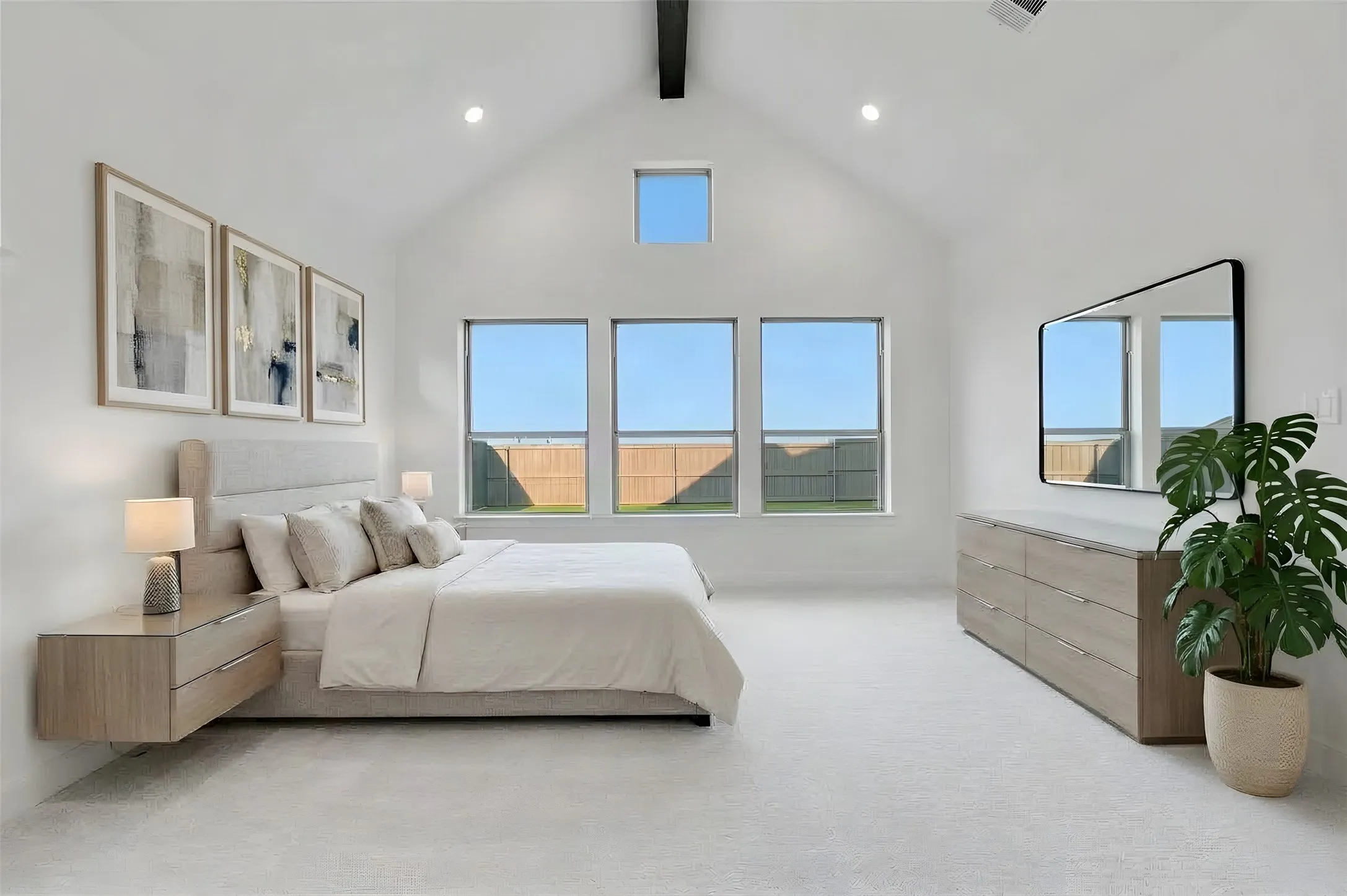 Vaulted ceiling with exposed beam, recessed lighting, three large windows, and a high transom window