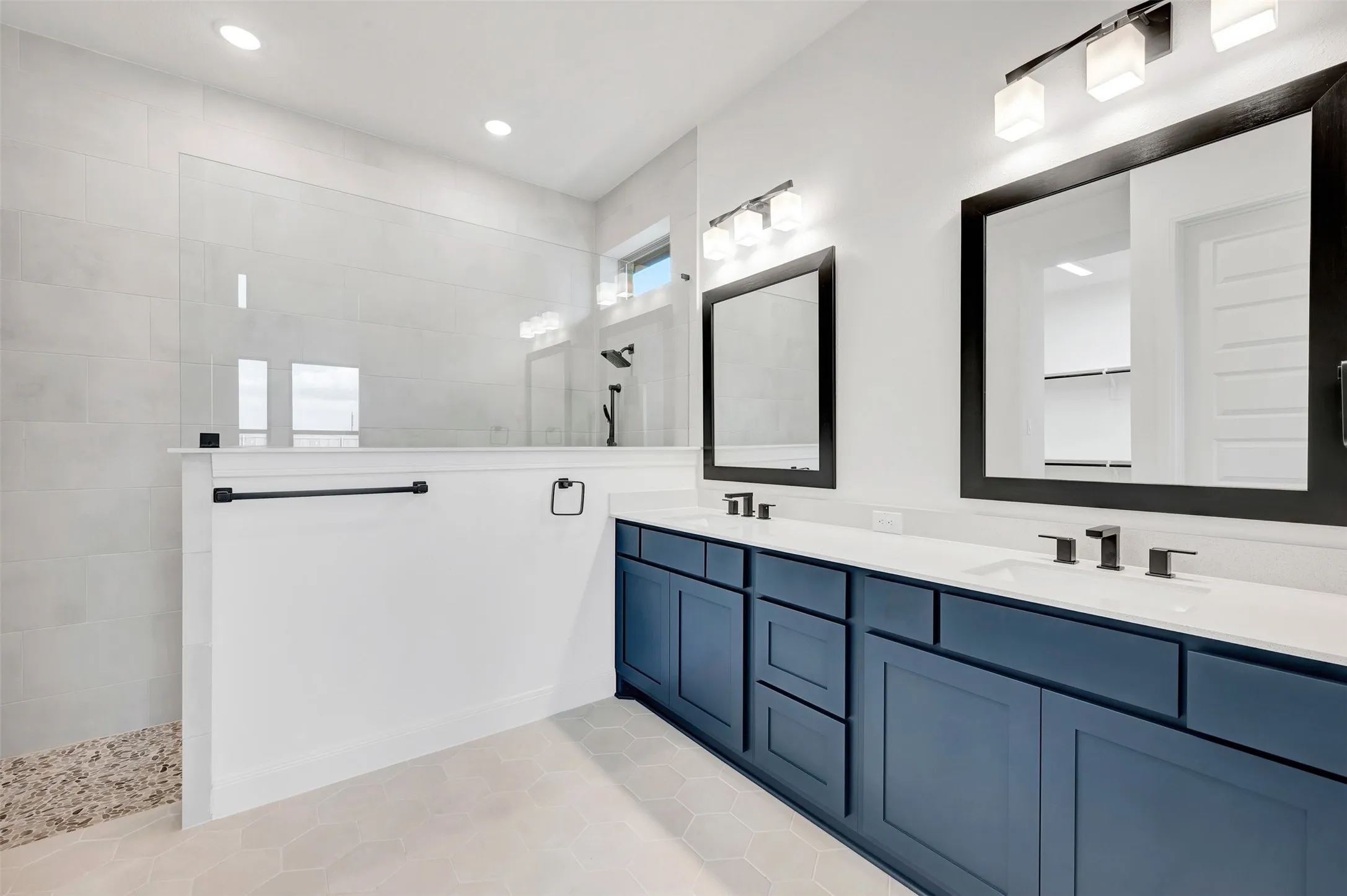 Dual vanity with dark blue cabinetry and undermount sinks, matte black framed mirrors, and contemporary lighting